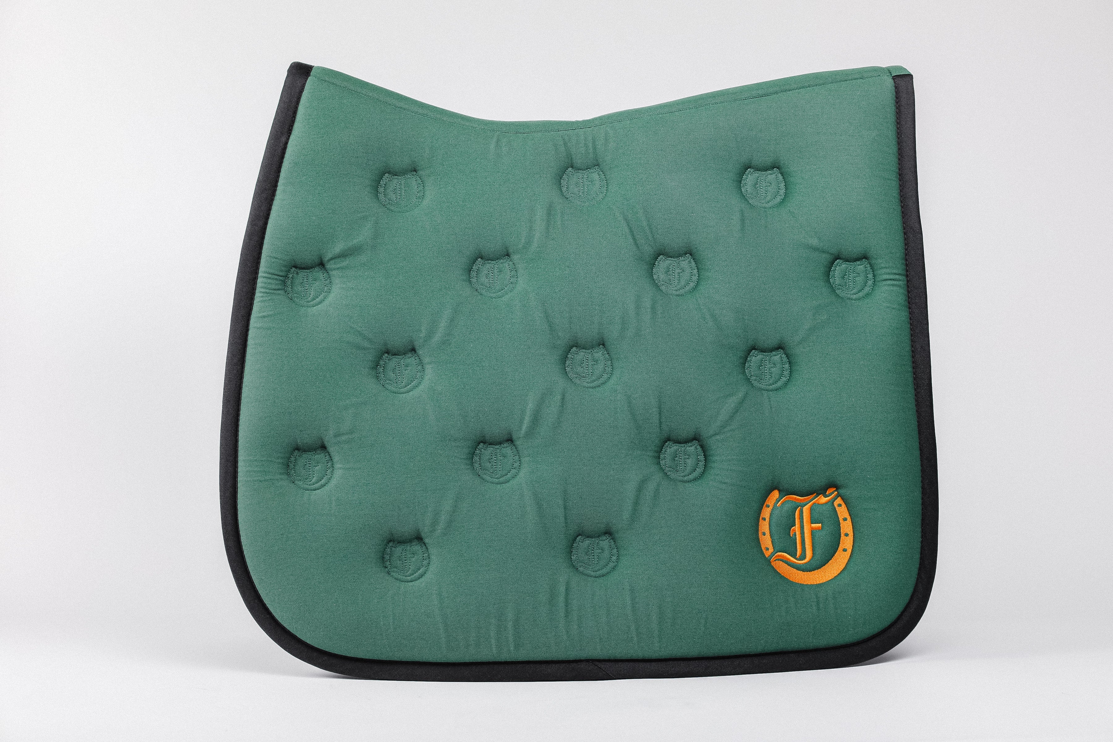 Green quilted saddle pad, showcasing the bamboo lining, Freedmans's logo embroidery, and Freedmans's logo pattern quilting.