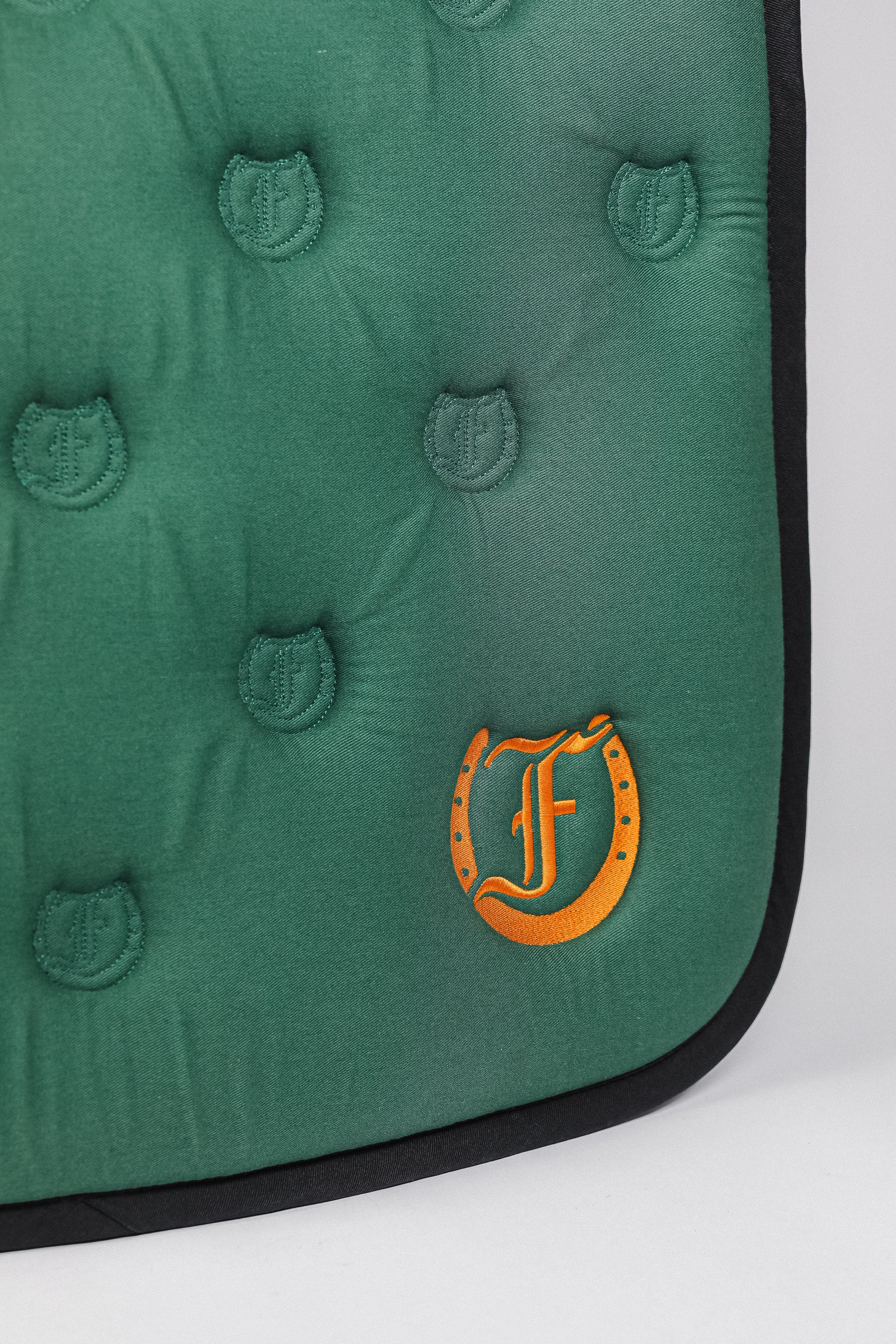 Detailed view of the Freedman’s logo and the Freedman’s logo pattern quilting on a green saddle pad.