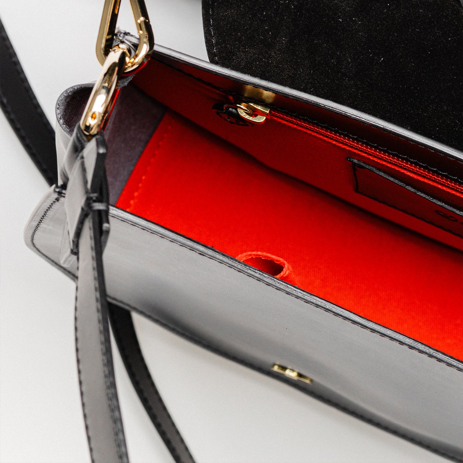 Detailed view of the interior of the Freedman's Burghley Shoulder Bag, showcasing its vibrant red lining and practical organization.