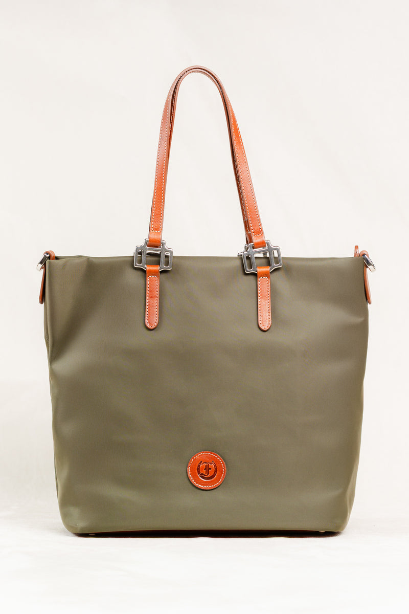 Freedman's Conestoga Tote in olive green, full view showing the bag's shape, texture, brown leather handles and trim, and the brand's circular logo patch centered on the front.