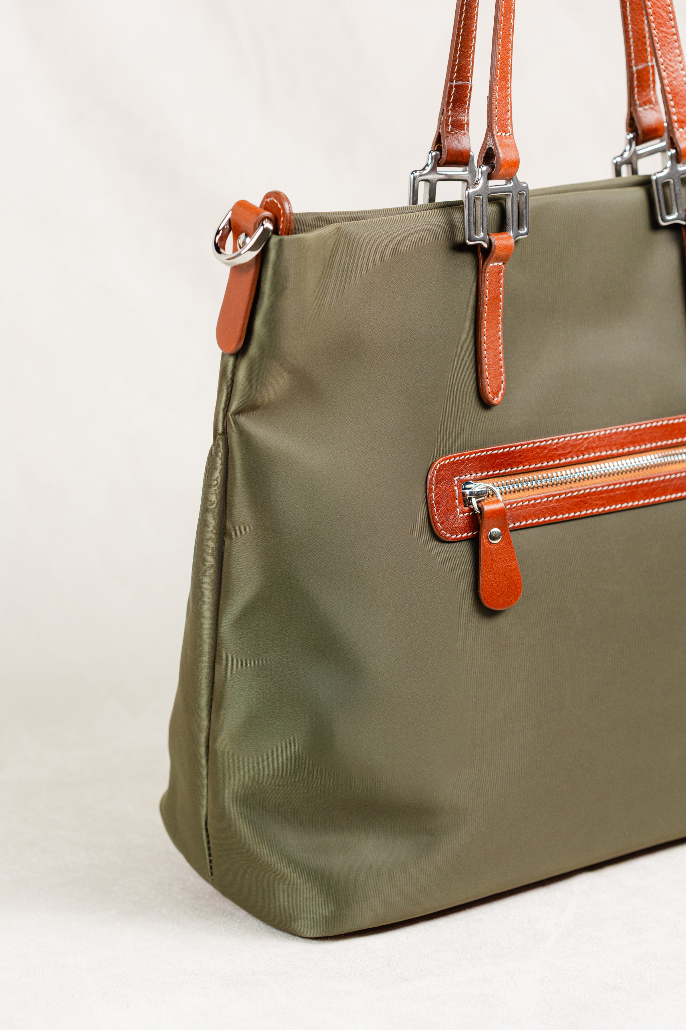 Freedman's Conestoga Tote in olive green, detailed side view showcasing the bag's shape, back zipper pocket with red zipper teeth, brown leather handles with silver hardware, and the bag's smooth fabric texture