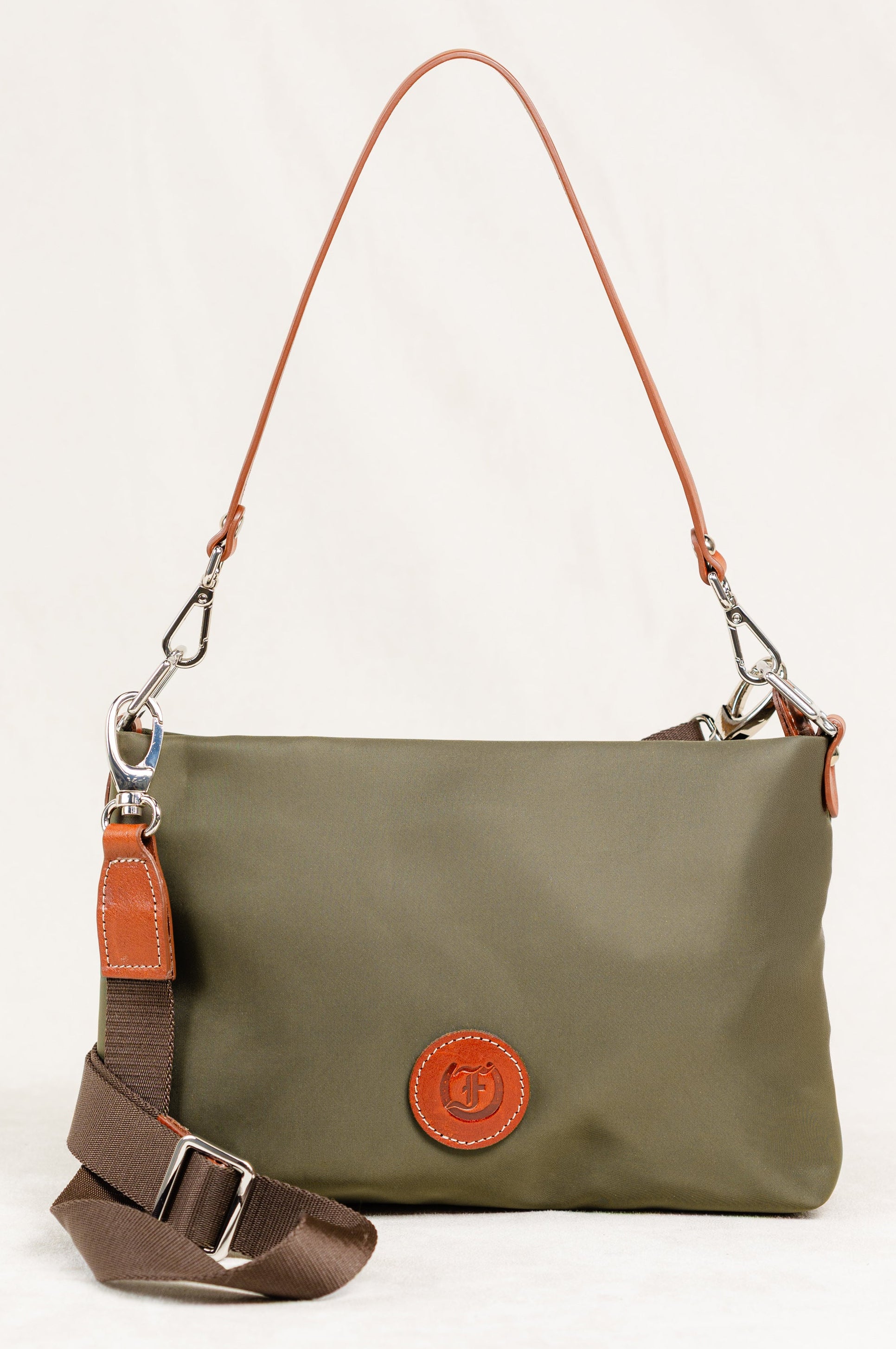 Freedman's Dokar Bag in olive green, close-up shot showing the bag's texture, brown leather accents, detachable shoulder and crossbody straps, and the brand's circular logo patch.