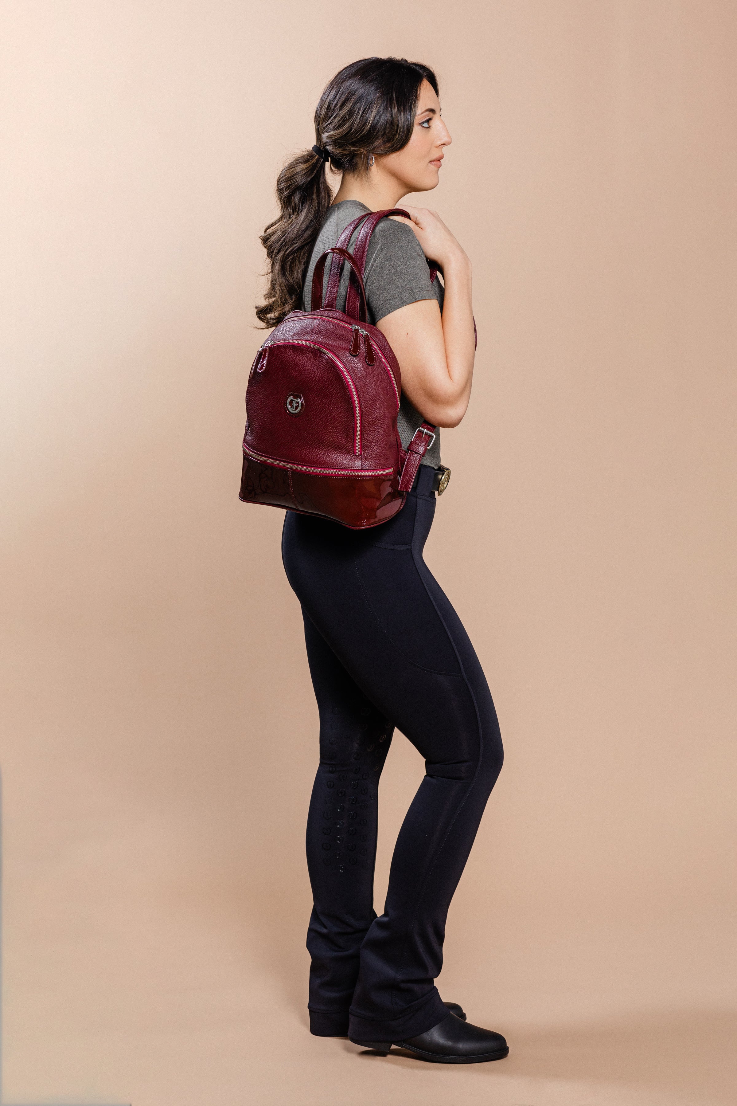 A woman wearing a burgundy Brougham Backpack.-side view