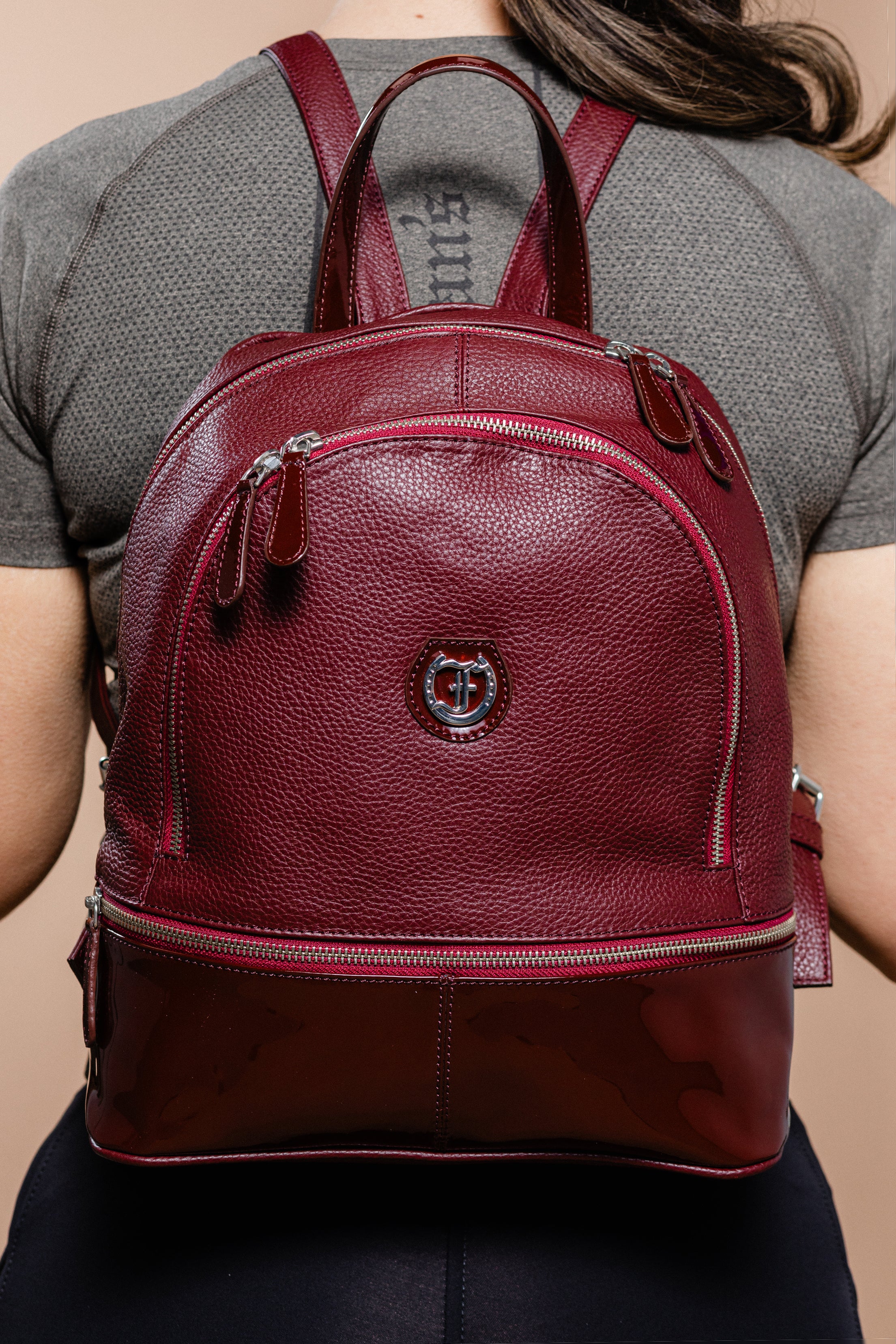 A woman wearing a burgundy Brougham Backpack.
