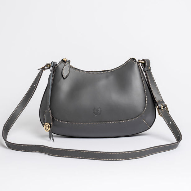 Carlisle Bag in grey leather by Freedman Harness – curved beige crossbody handbag with gold hardware, adjustable strap, and minimalist silhouette