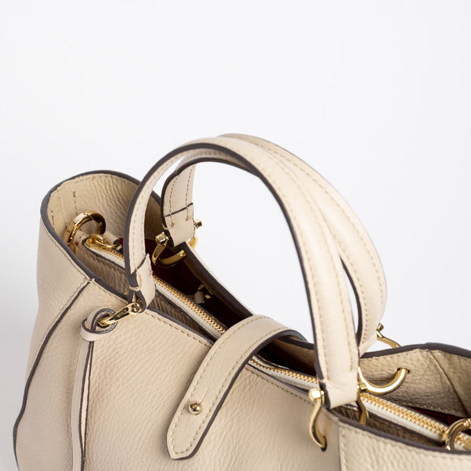 Close-up of Midi Cabriolet Bag by Freedman Harness – beige pebbled leather, dual top handles, gold zipper closure, and polished hardware details