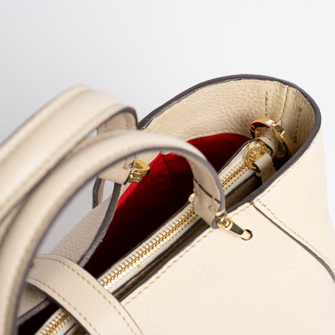 Interior view of Midi Cabriolet Bag by Freedman Harness – beige leather exterior with vibrant red lining, gold zipper, and structured handles