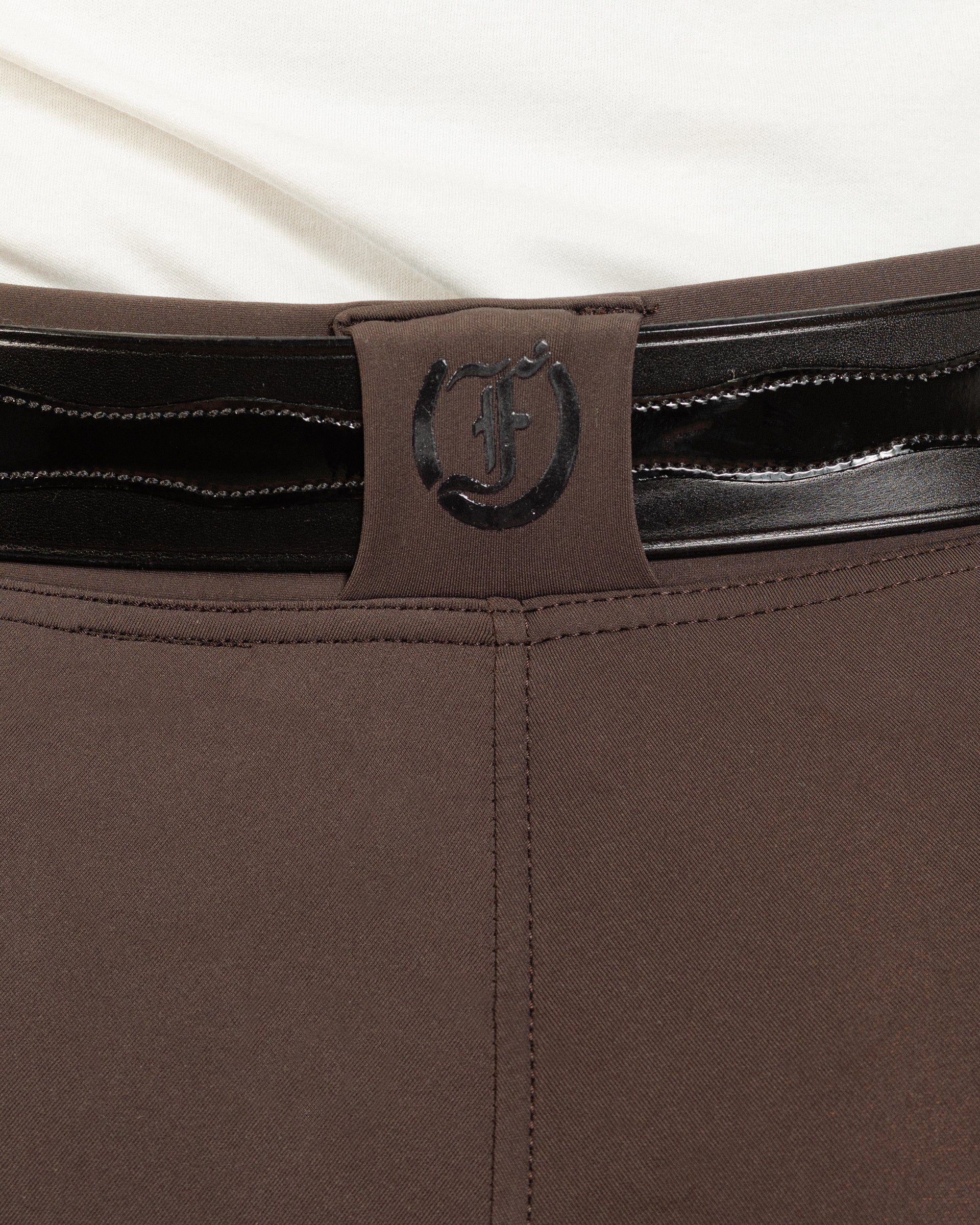Back view of After Dark Brown Jods with a Patent Scalloped Spur Belt and Freedman’s “F” logo by Freedman’s Harness on a beige background.