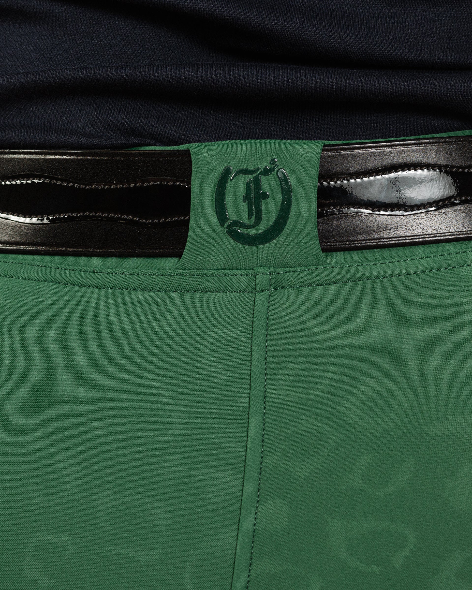 Back view of Green Cheetah Jods with a Patent Scalloped Spur Belt and Freedman’s “F” logo by Freedman’s Harness on a beige background.
