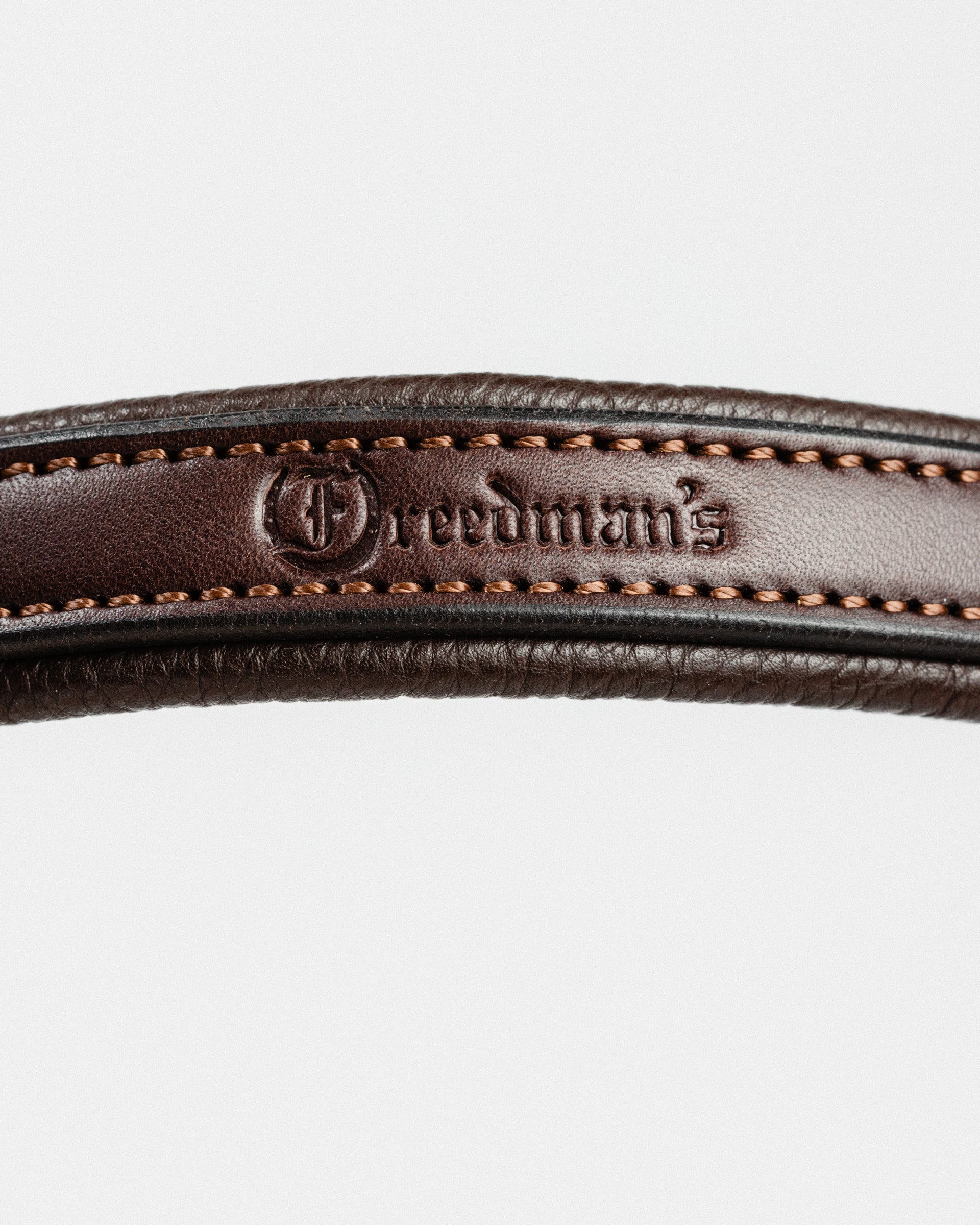 Close-up of dark brown leather, showcasing the embossed "Freedman's" brand name and detailed stitching along the edge.