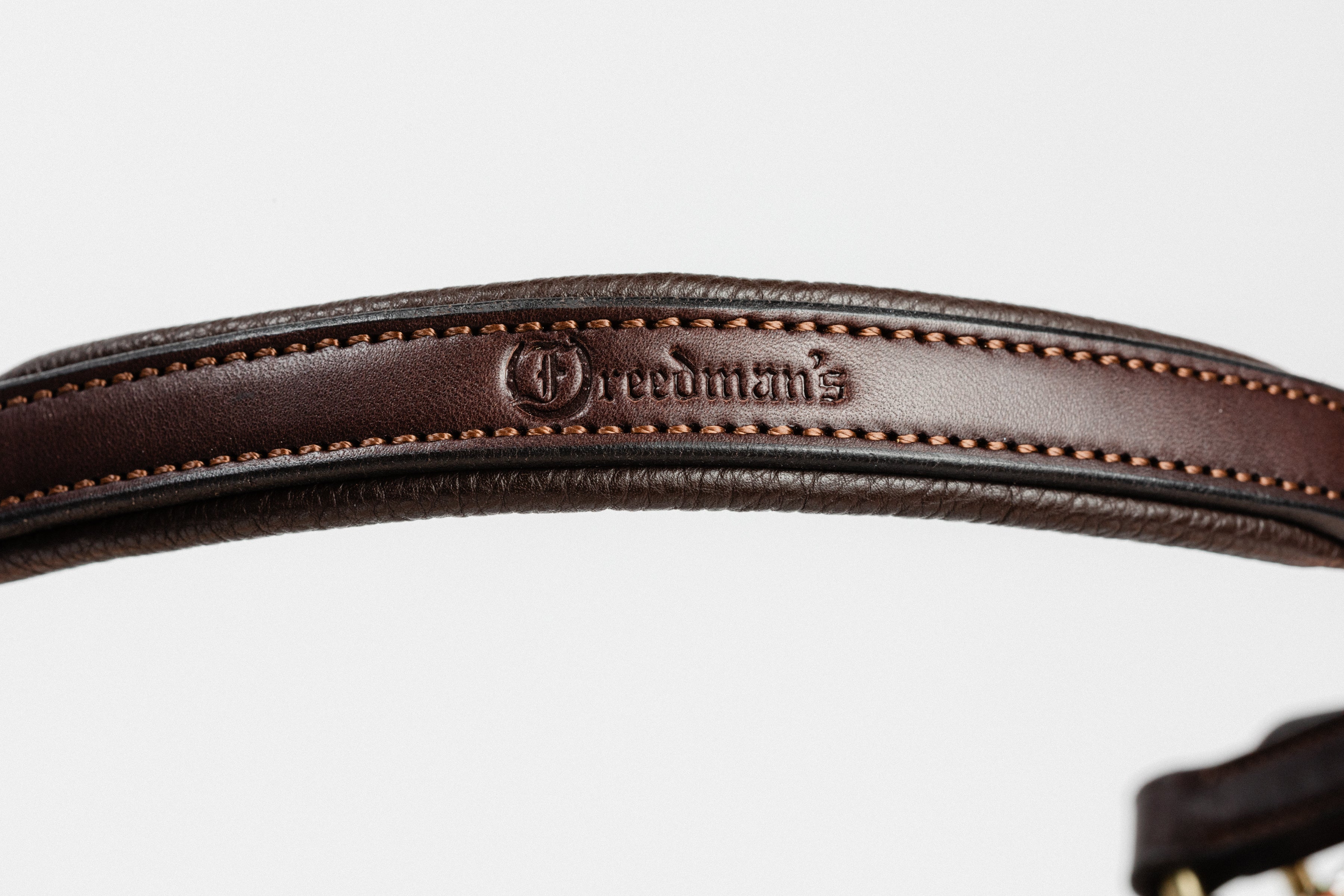 Close-up of dark brown leather, showcasing the embossed "Freedman's" brand name and detailed stitching along the edge.