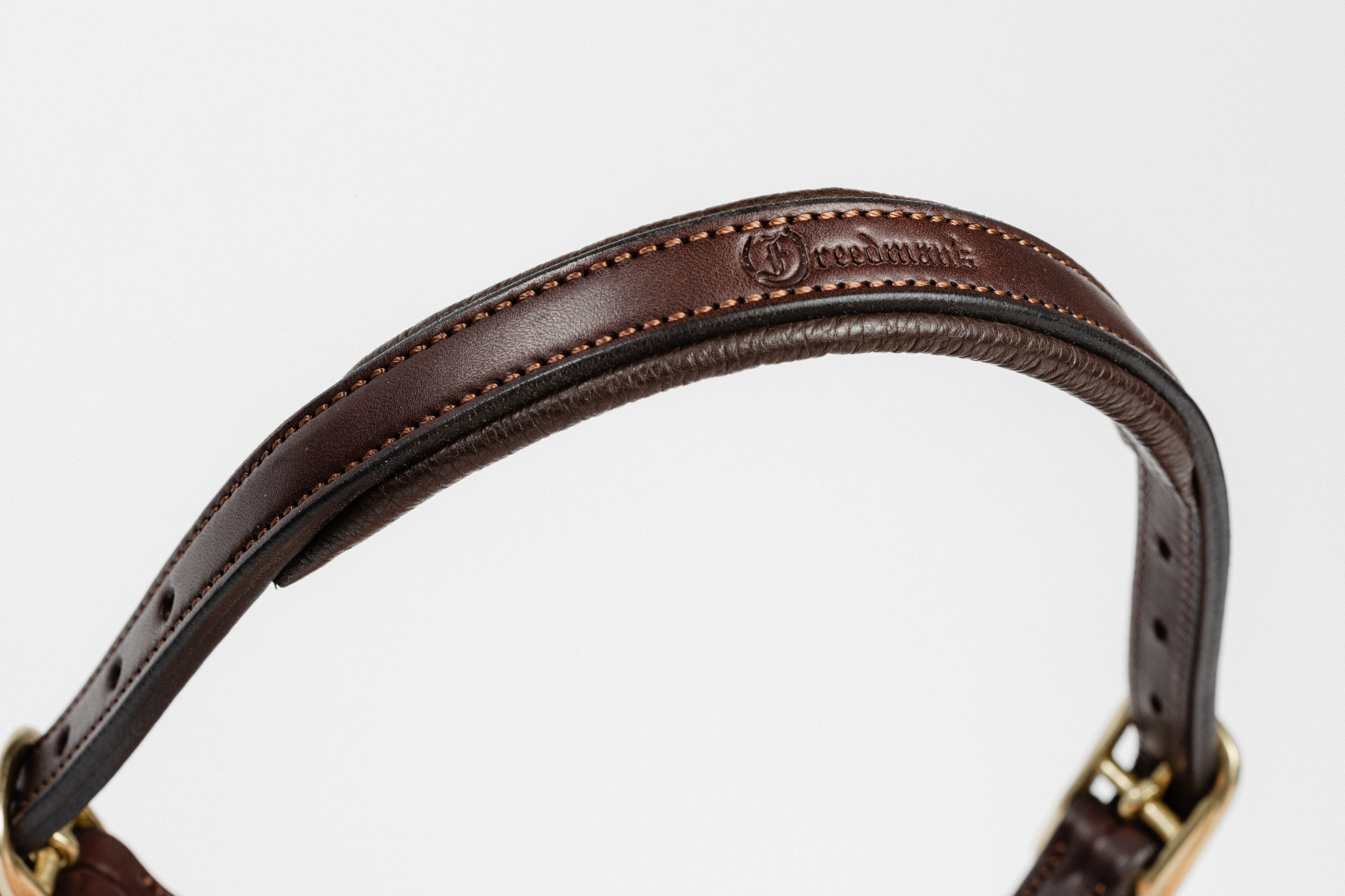 Close-up of a dark brown leather strap with brass buckle, showcasing the fine stitching and the "Freedman" brand embossed on the leather.