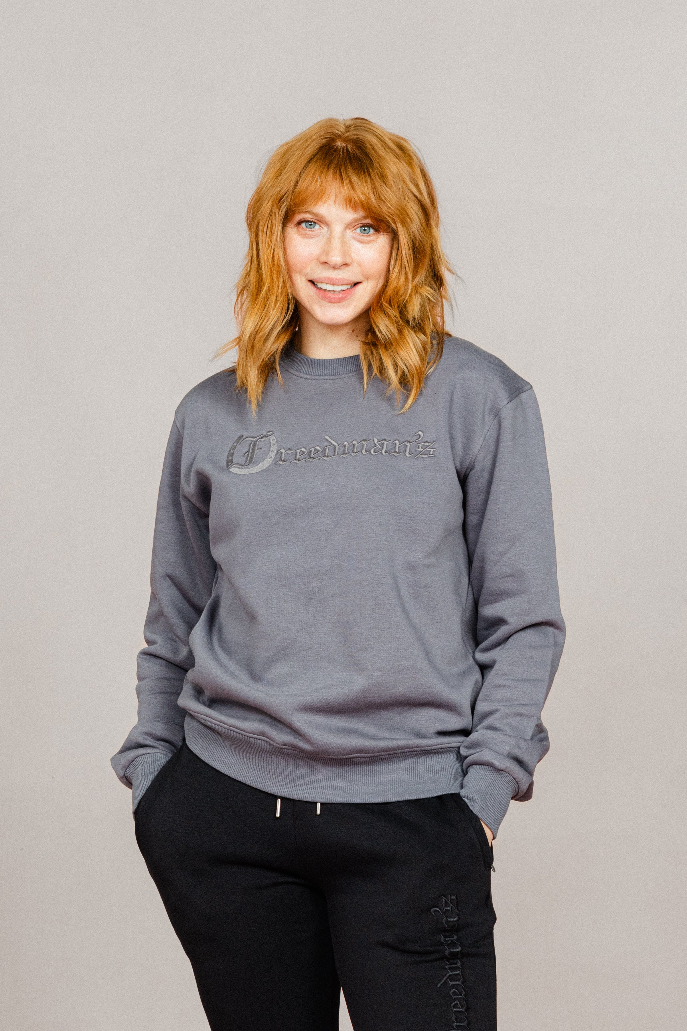 Woman wearing the Ash Grey Freedman's embroidered crewneck sweatshirts. These stylish and cozy sweatshirts feature a tonal Freedman’s logo, perfect for casual wear and layering