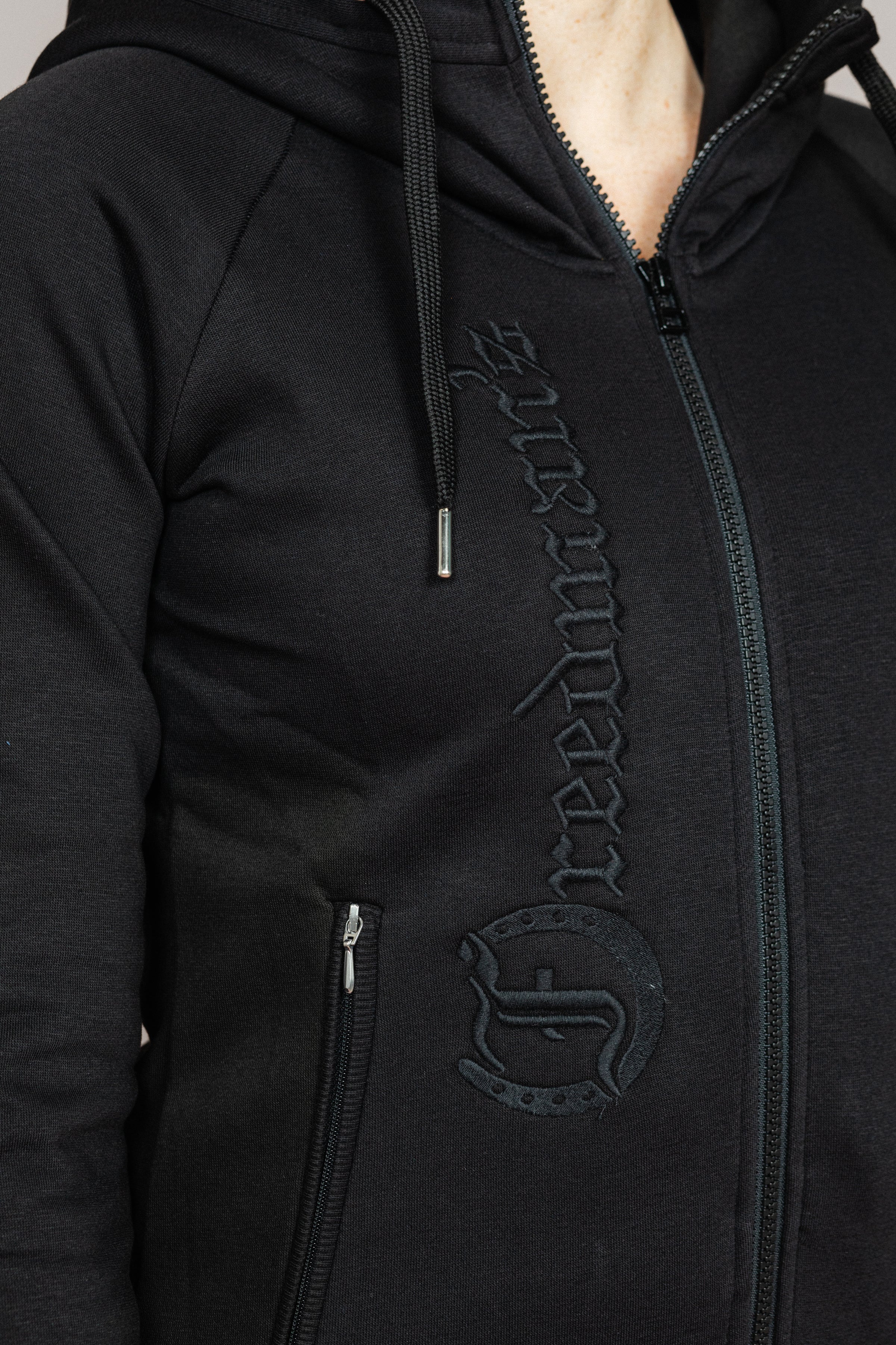 Black Ladies' Logo Hoodie by Freedman's, close-up showing embroidered "Freedman's" logo down the front and full zip closure.