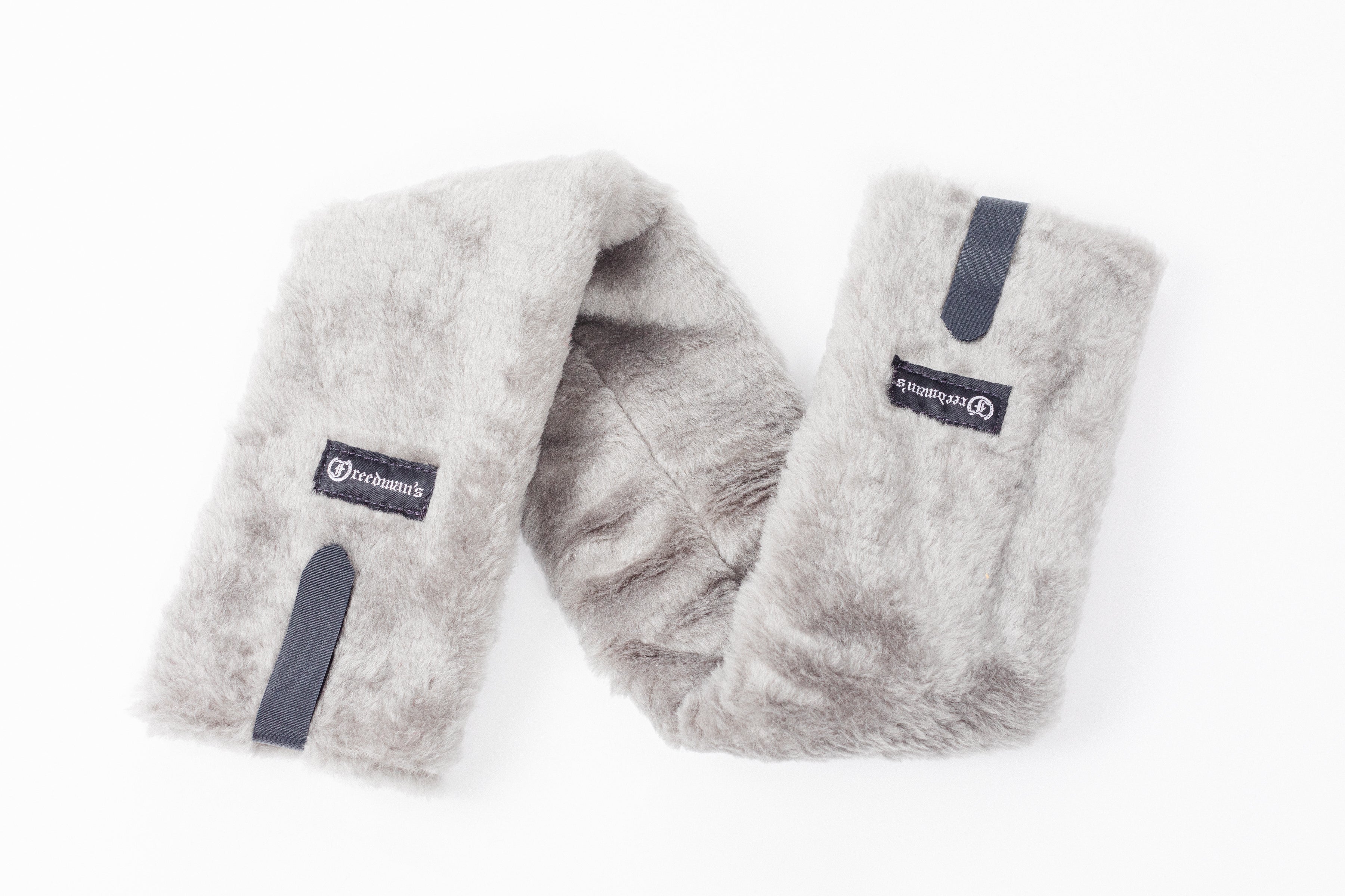 Close-up of Freedman's Fleece Breast Collar Pad, grey fabric with logo patches, equestrian equipment.