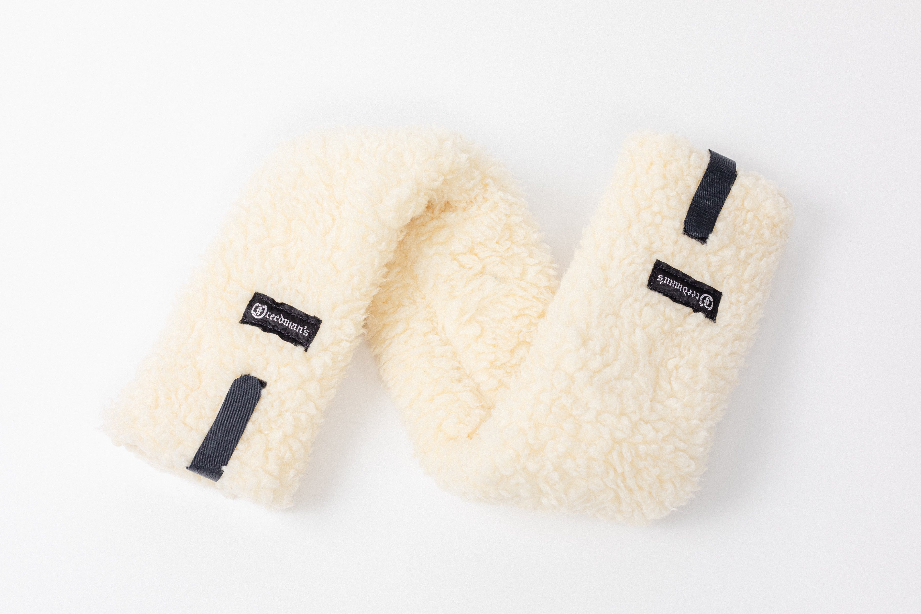 Close-up of Freedman's Fleece Breast Collar Pad, Natural fabric with logo patches, equestrian equipment.