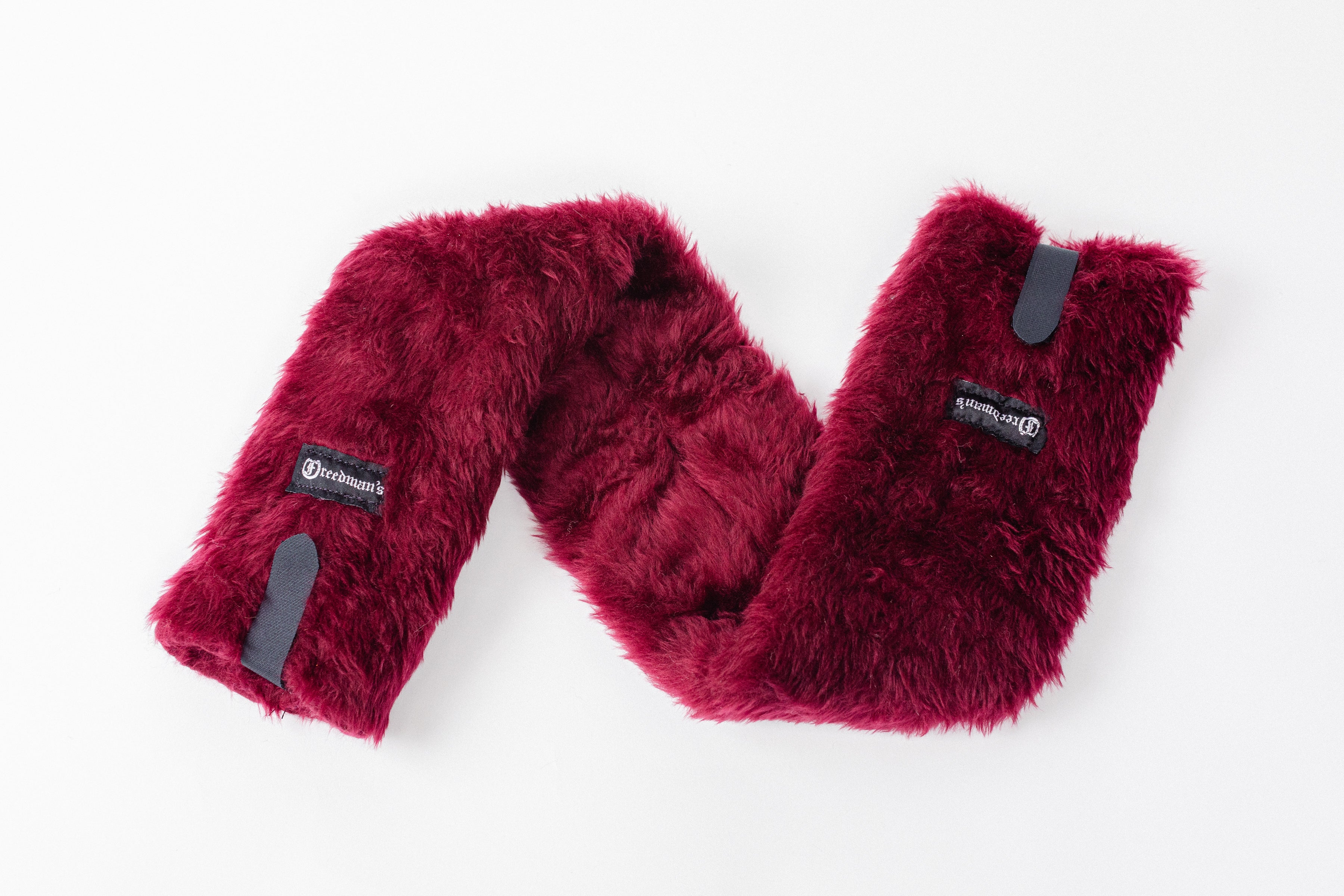 Close-up of Freedman's Fleece Breast Collar Pad, burgundy  fabric with logo patches, equestrian equipment.