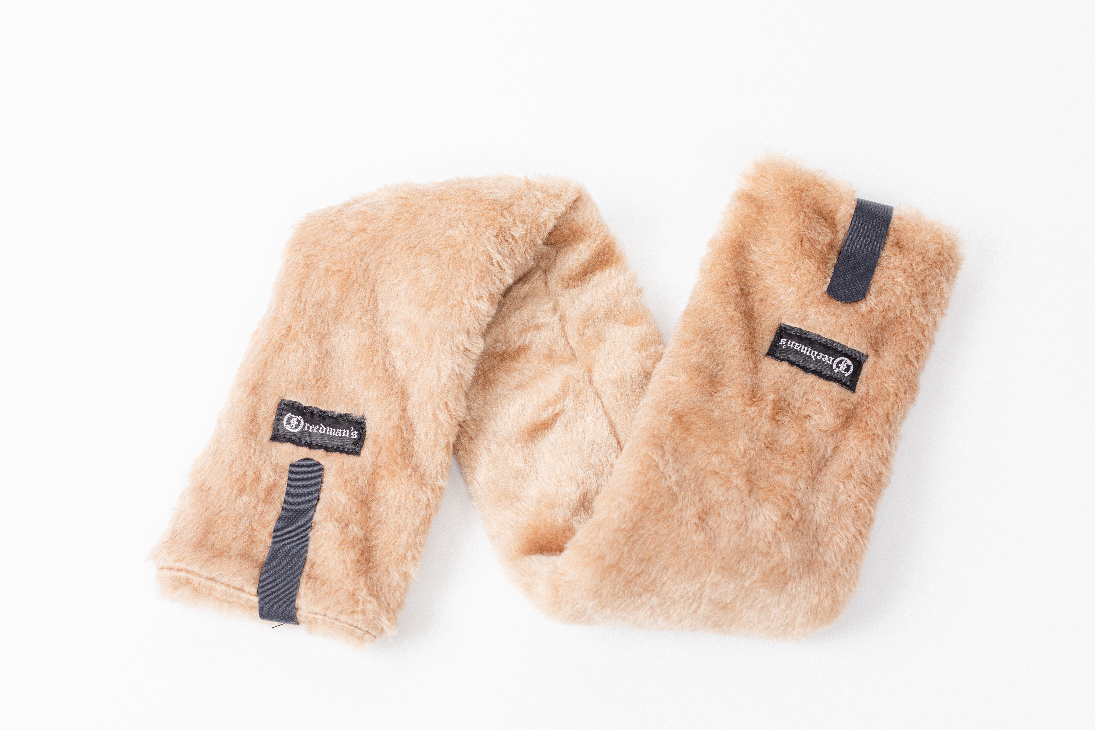 Close-up of Freedman's Fleece Breast Collar Pad, tan fabric with logo patches, equestrian equipment.
