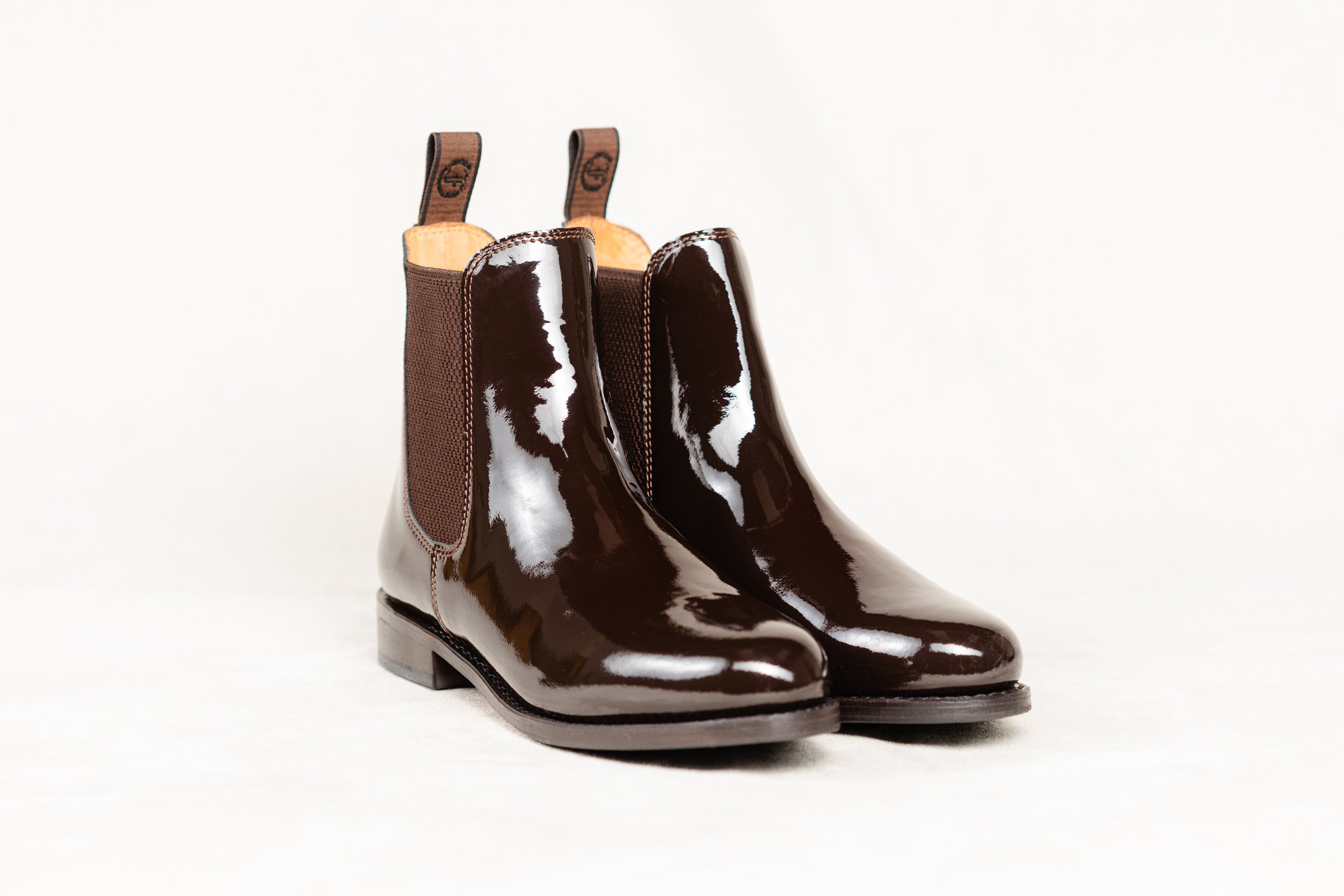 Pair of brown patent leather Adelaide Show Jodhpur Boots, isolated on a white background.