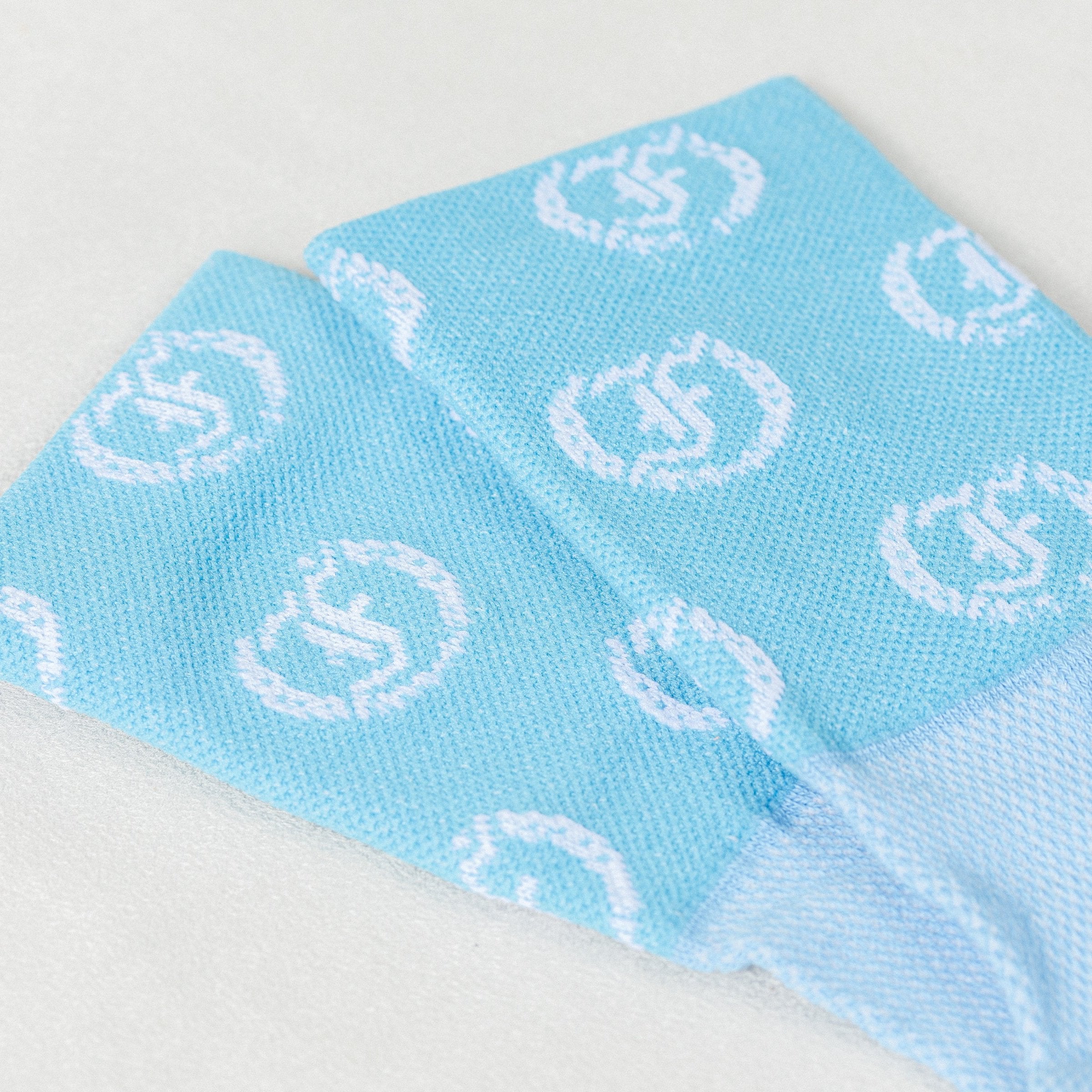 Light blue socks with repeating light Freedman's logo, close-up with visible knit texture.