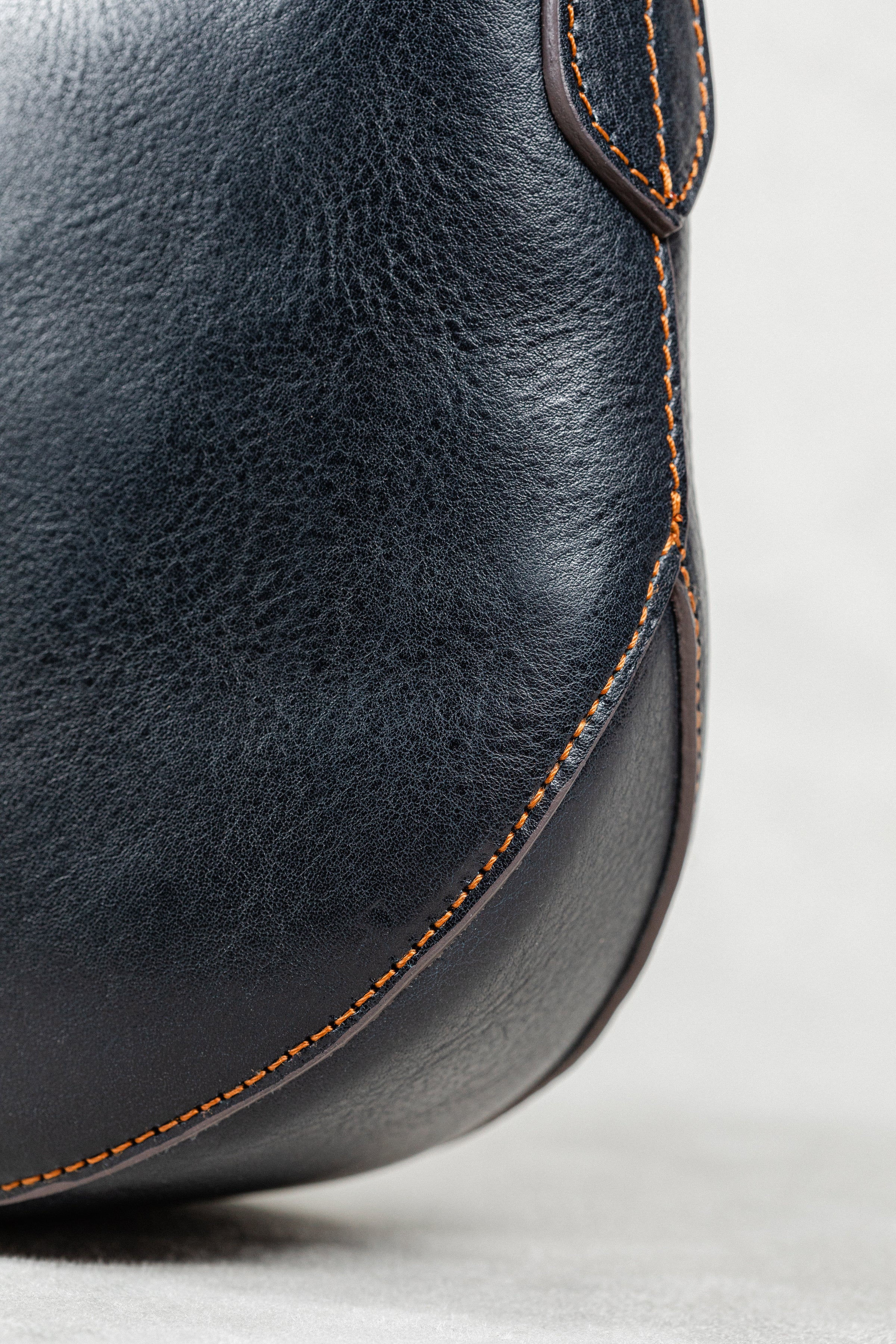 Detail Shot of Freedman's Murphy Bag, Emphasizing the Dark Navy Leather Grain and Orange Hand-Stitched Seam