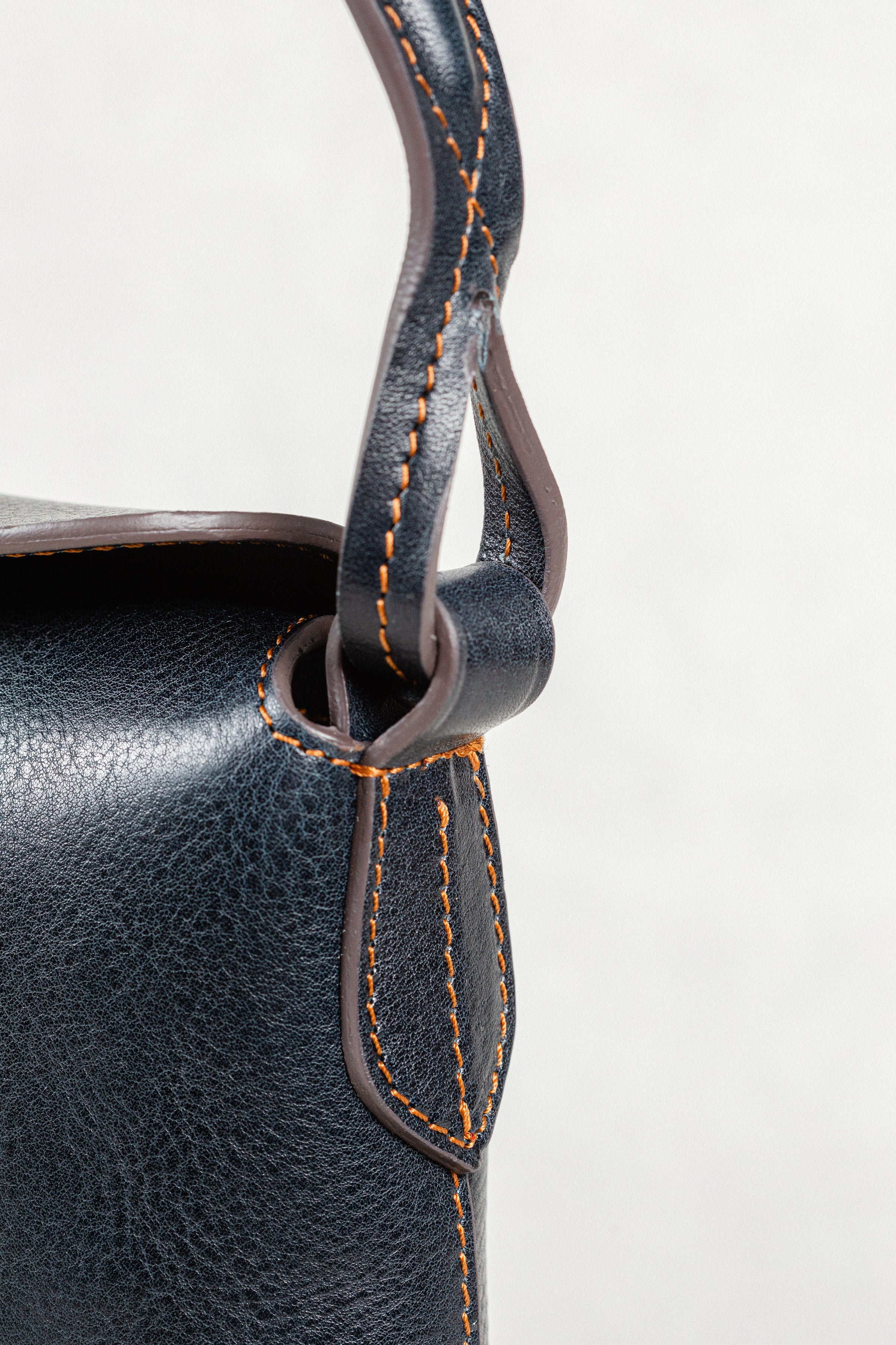 Close-up of Freedman's Murphy Bag Handle, Dark Navy Leather with Visible Orange Stitching and Hardware Attachment