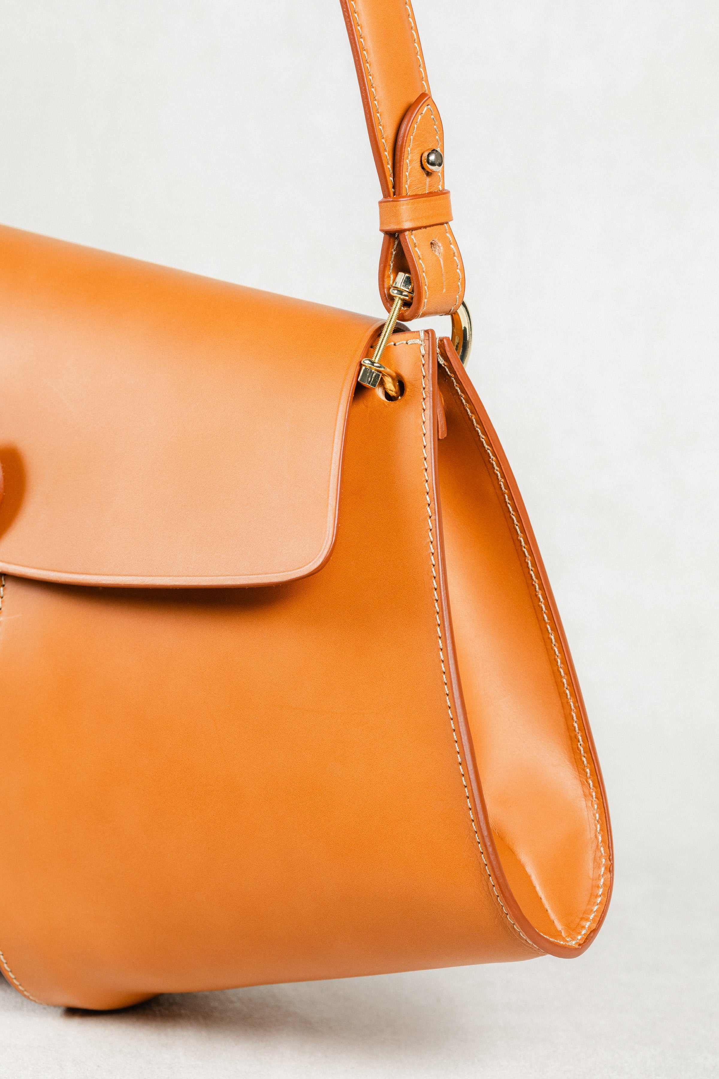 Close-up of Cognac leather Moray Bag by Freedman's, highlighting gold-tone hardware, adjustable strap, flap detail, and contrasting stitching.