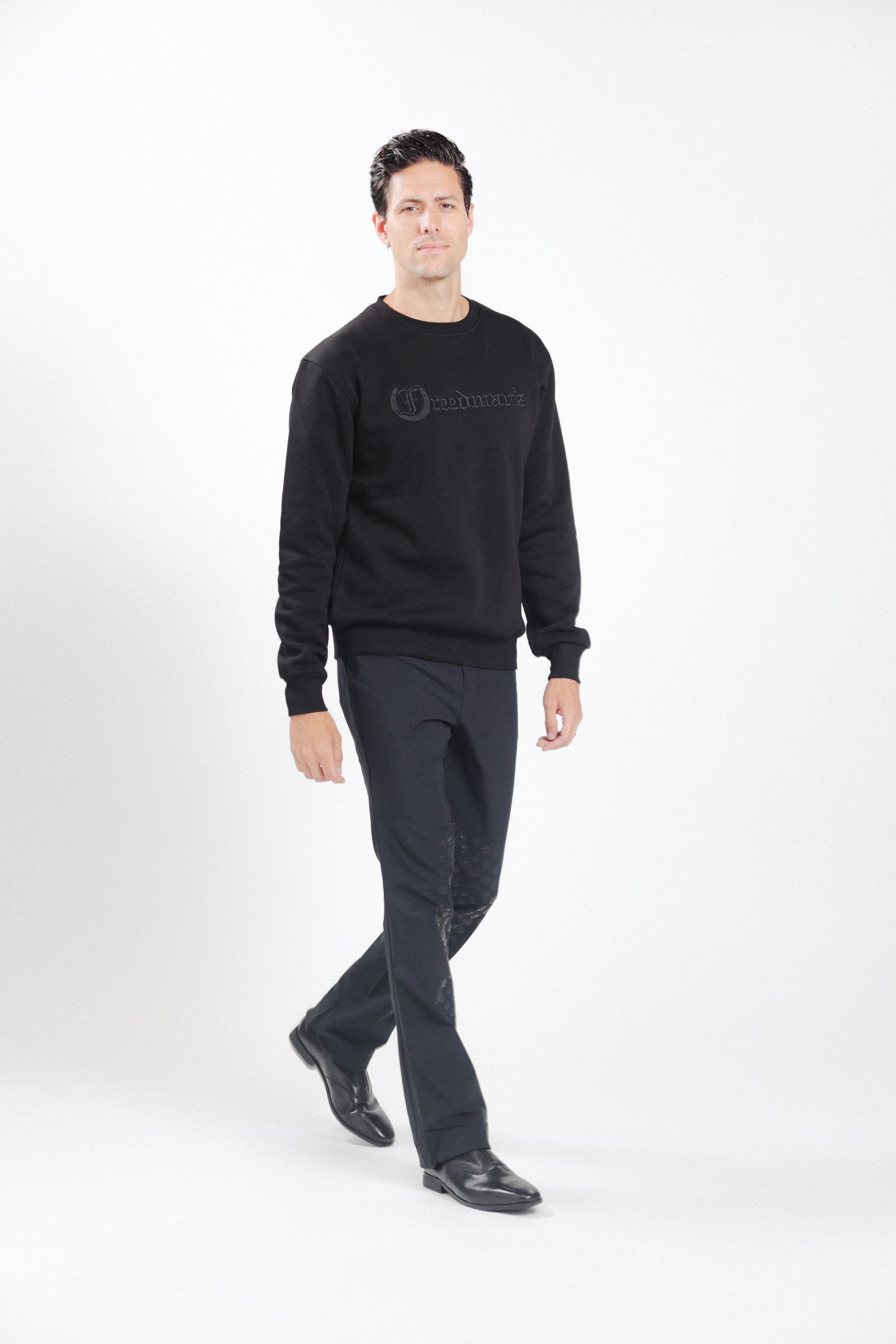 Man wearing Freedman's embroidered crewneck sweatshirts in black. These stylish and cozy sweatshirts feature a tonal Freedman’s logo, perfect for casual wear and layering