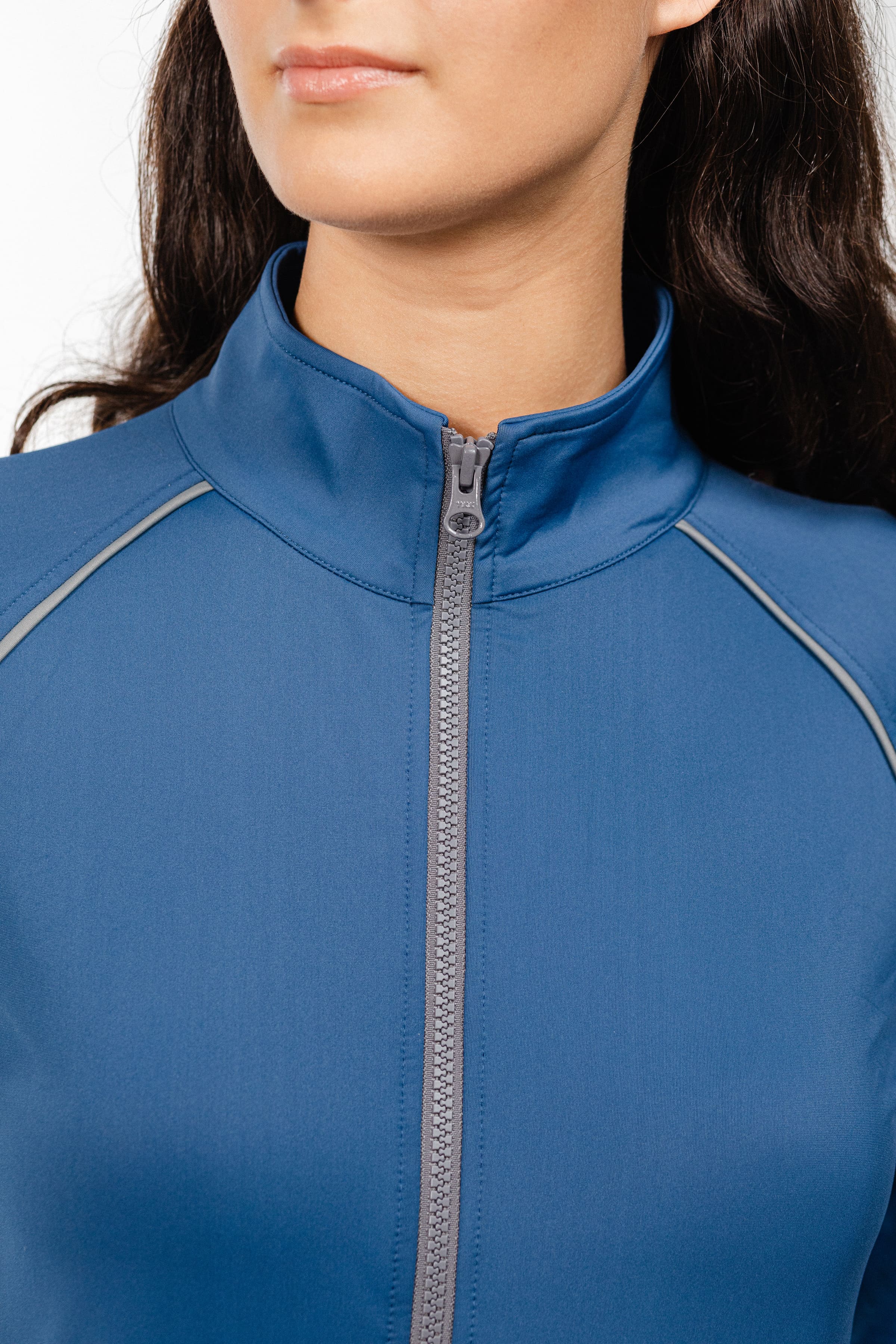 Close-up detail of Ladies Arum Jacket by Freedman's in purple, showing high collar design, black zipper, and contrast piping construction, highlighting quality stitching and fabric texture on woman with dark hair against white background