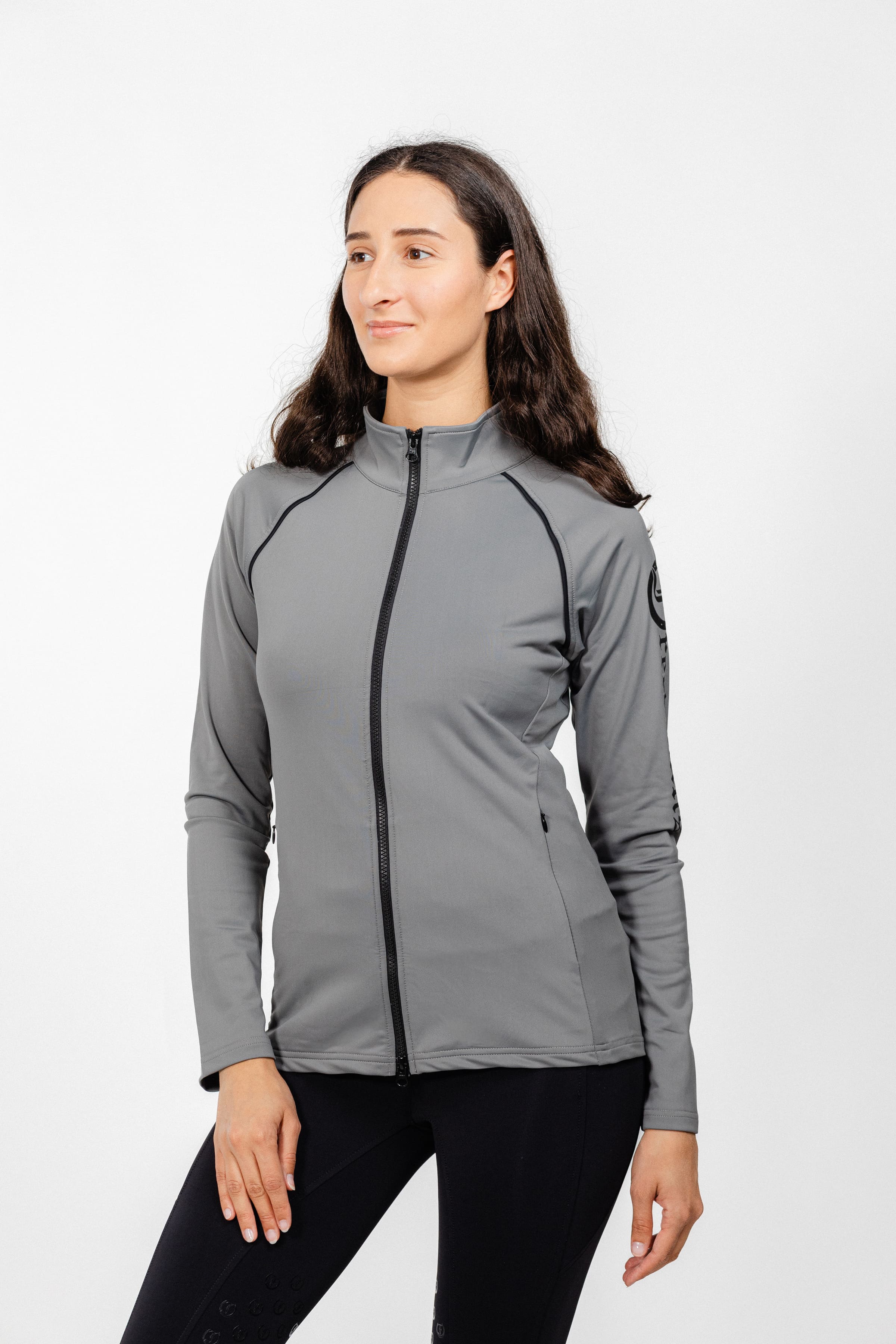Ladies Arum Jacket by Freedman's in gray with black zipper detail, modeled by smiling woman with long dark hair wearing black pants against white background, showing athletic apparel fit and style