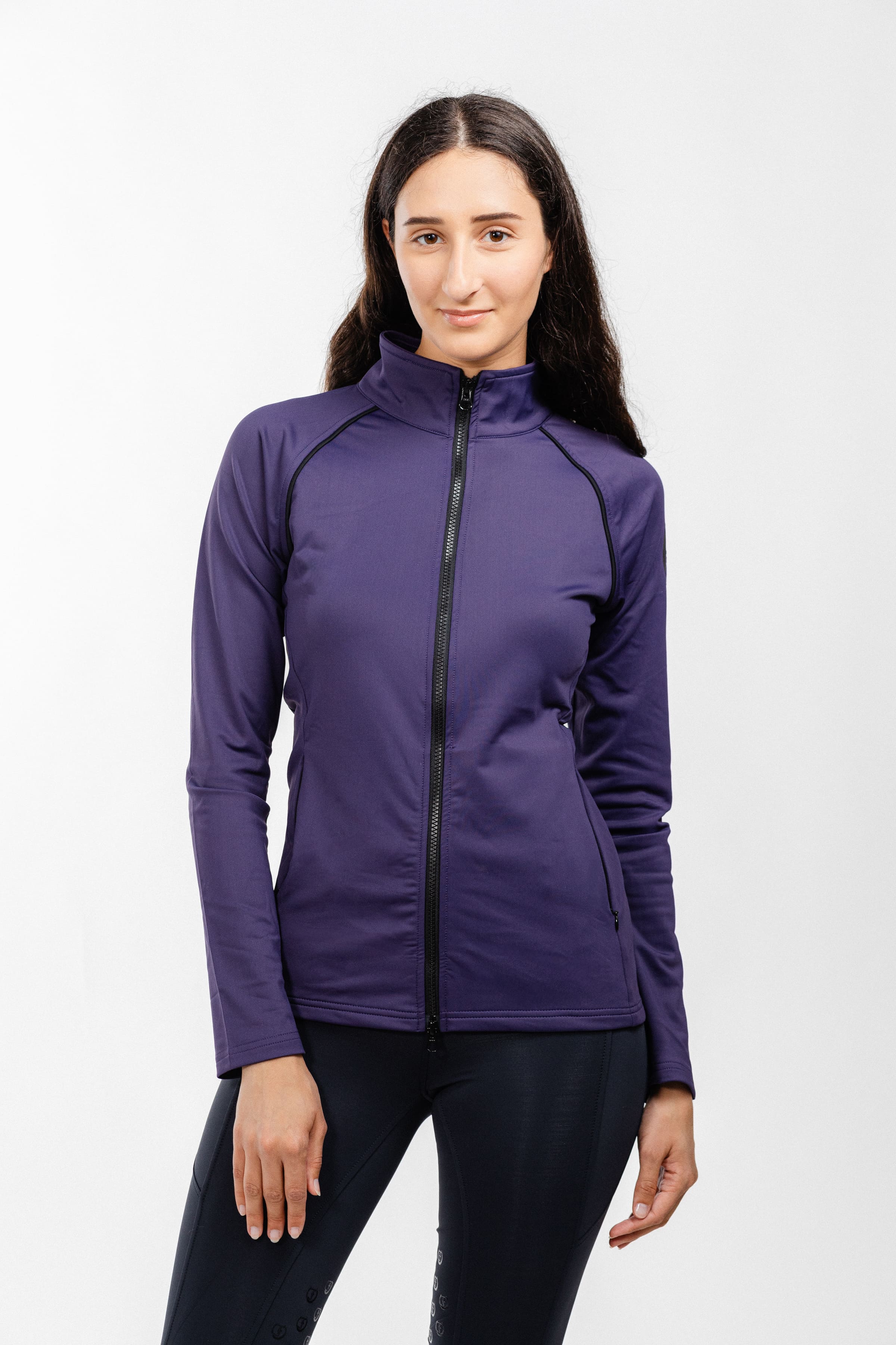Ladies Arum Jacket by Freedman's in purple with black zipper detail, modeled by smiling woman with long dark hair wearing black pants against white background, showing athletic apparel fit and style