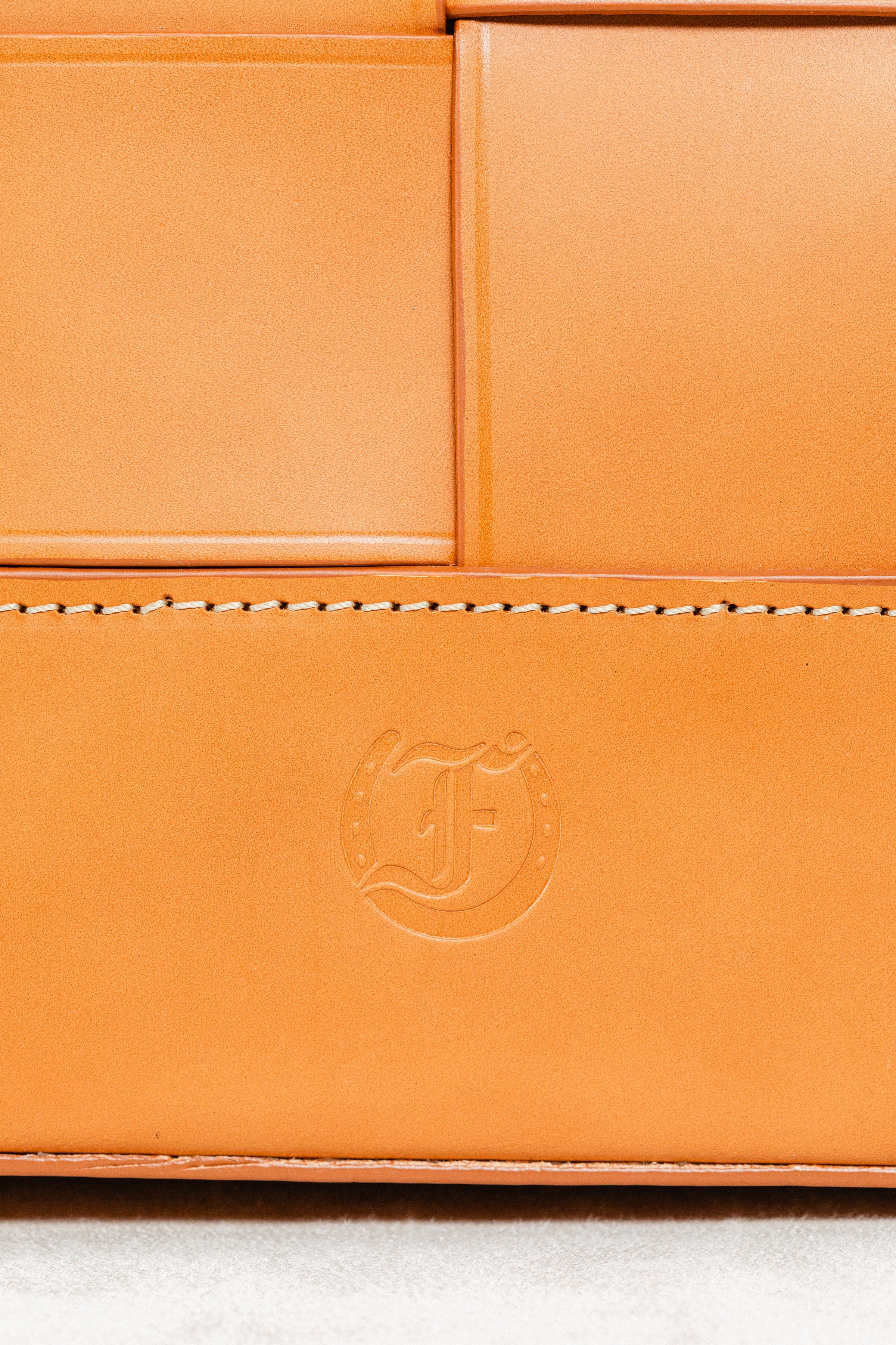 Close-up of Freedman's F logo embossed on cognac leather