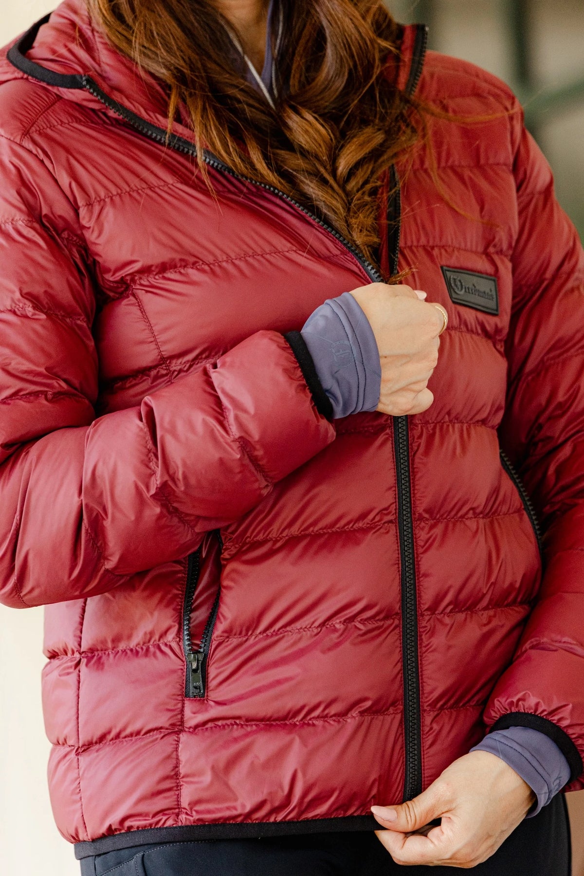 Close-up of the Signature Ladies' Packable Puffer Jacket in burgundy, highlighting the front zipper, quilted design, Freedman's logo patch, and zippered pockets.