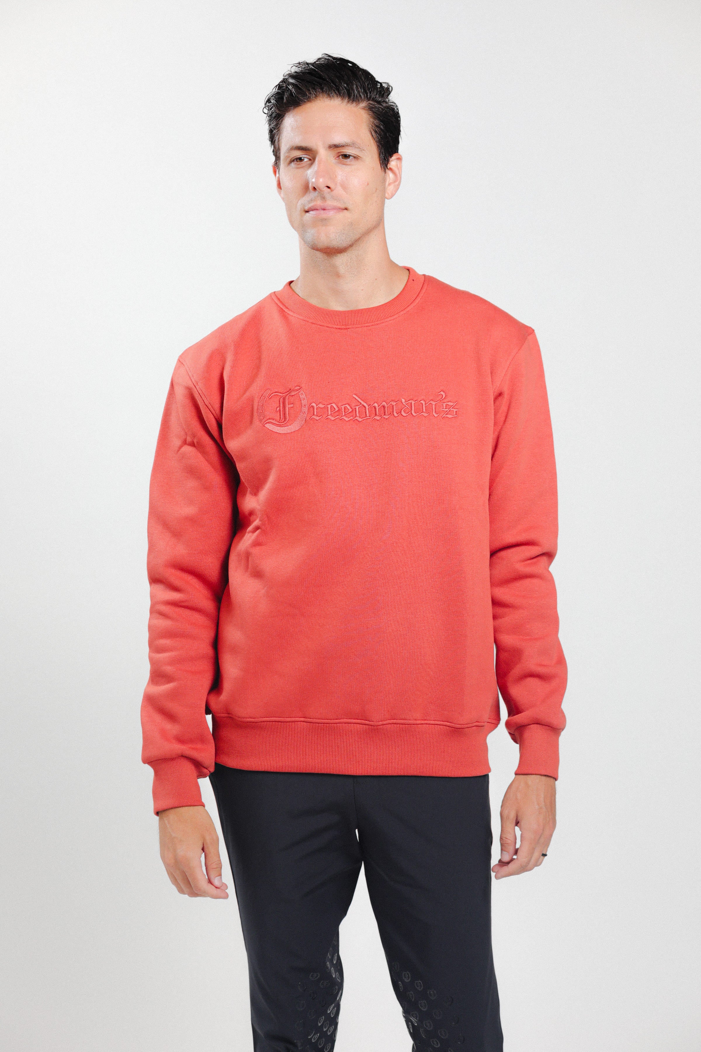 Man wearing Freedman's embroidered crewneck sweatshirts in Brick Red. These stylish and cozy sweatshirts feature a tonal Freedman’s logo, perfect for casual wear and layering