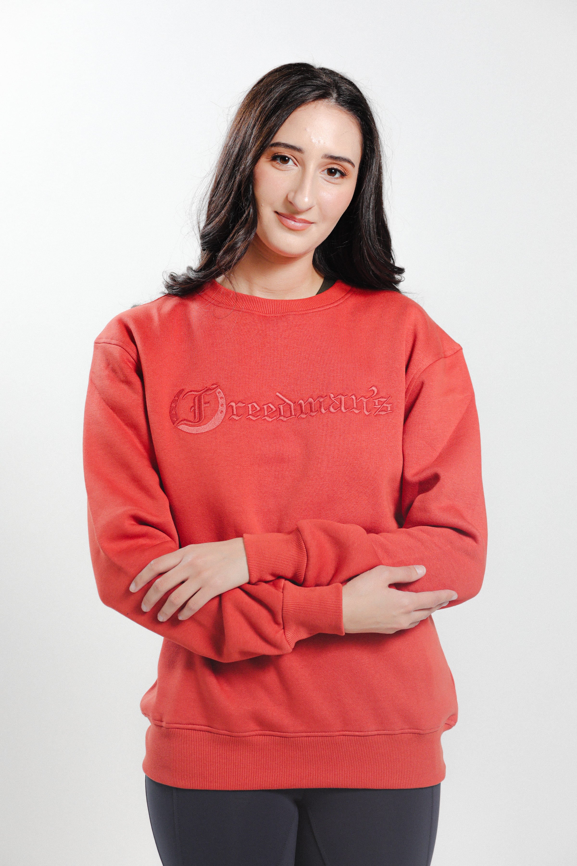Woman wearing the Brick Red Freedman's embroidered crewneck sweatshirts. These stylish and cozy sweatshirts feature a tonal Freedman’s logo, perfect for casual wear and layering