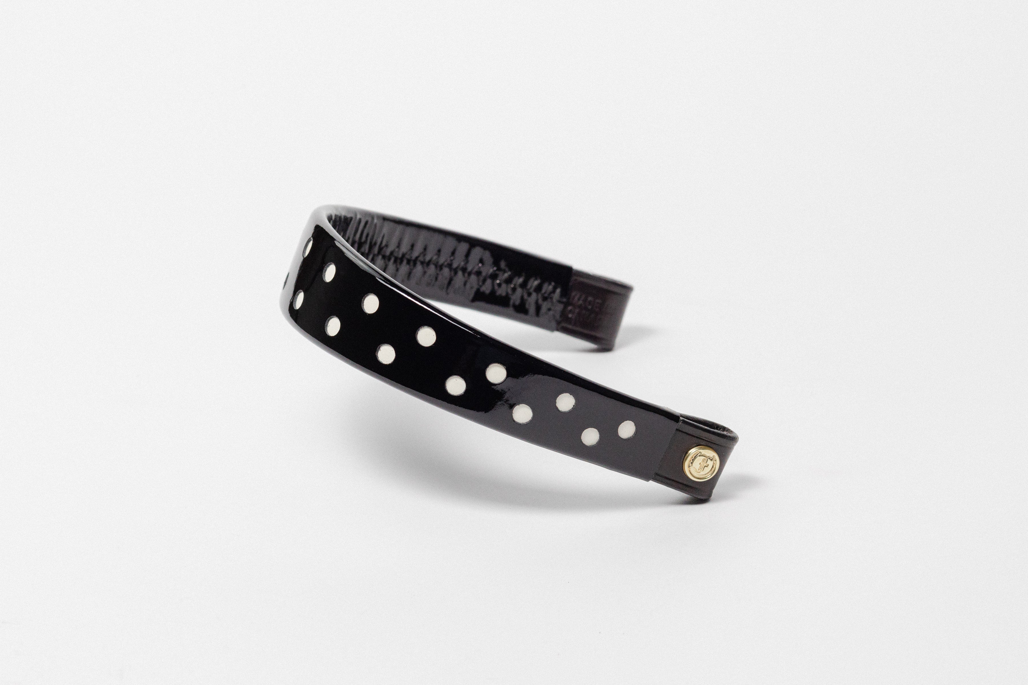 Black Patent Leather Browband with white dots, wide tapered design, polished brass Freedman logo buttons, and dark leather ends, angled view.