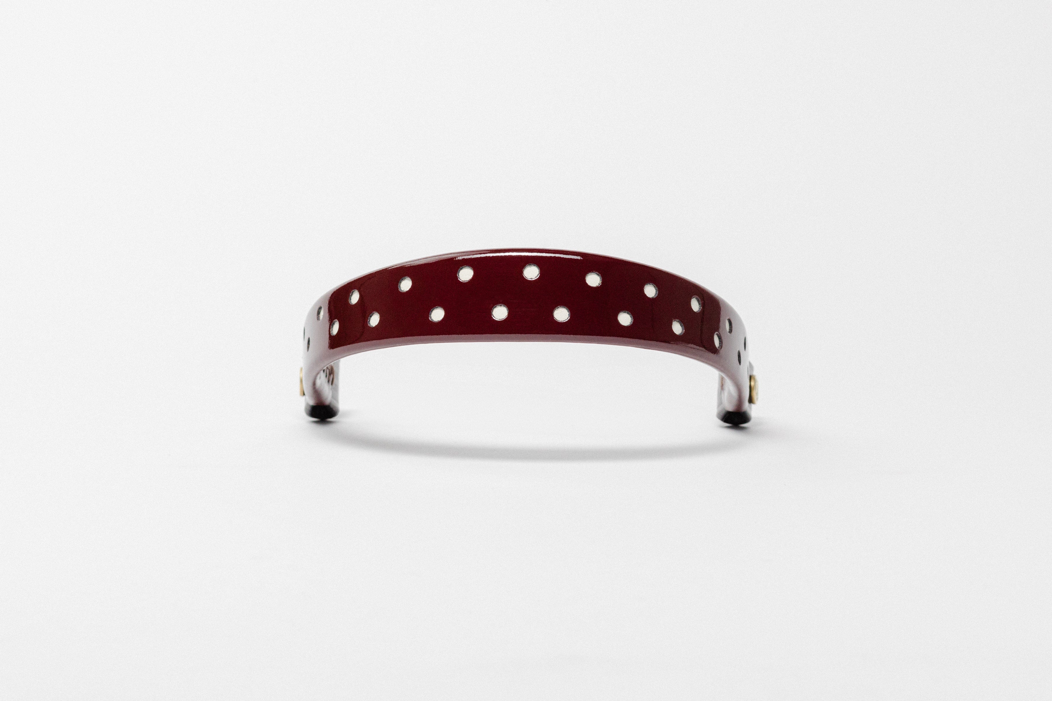 Burgundy Patent Leather Browband with small white dots, wide tapered design, polished brass Freedman logo buttons, and dark leather ends, frontal view.