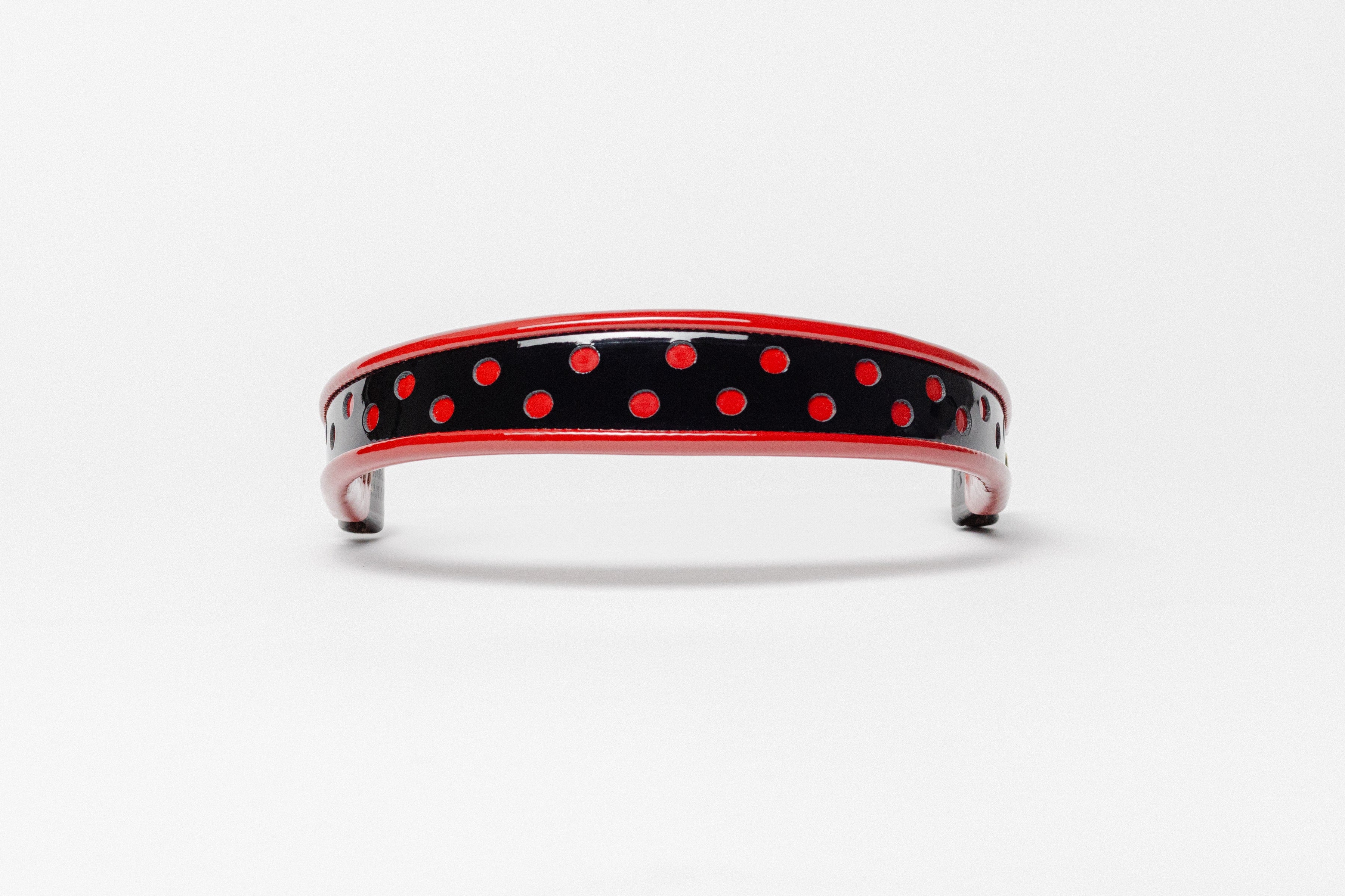 Red and Red dot patent leather browband, wide tapered design, turned edge, dark leather ends with gold button, shown flat.