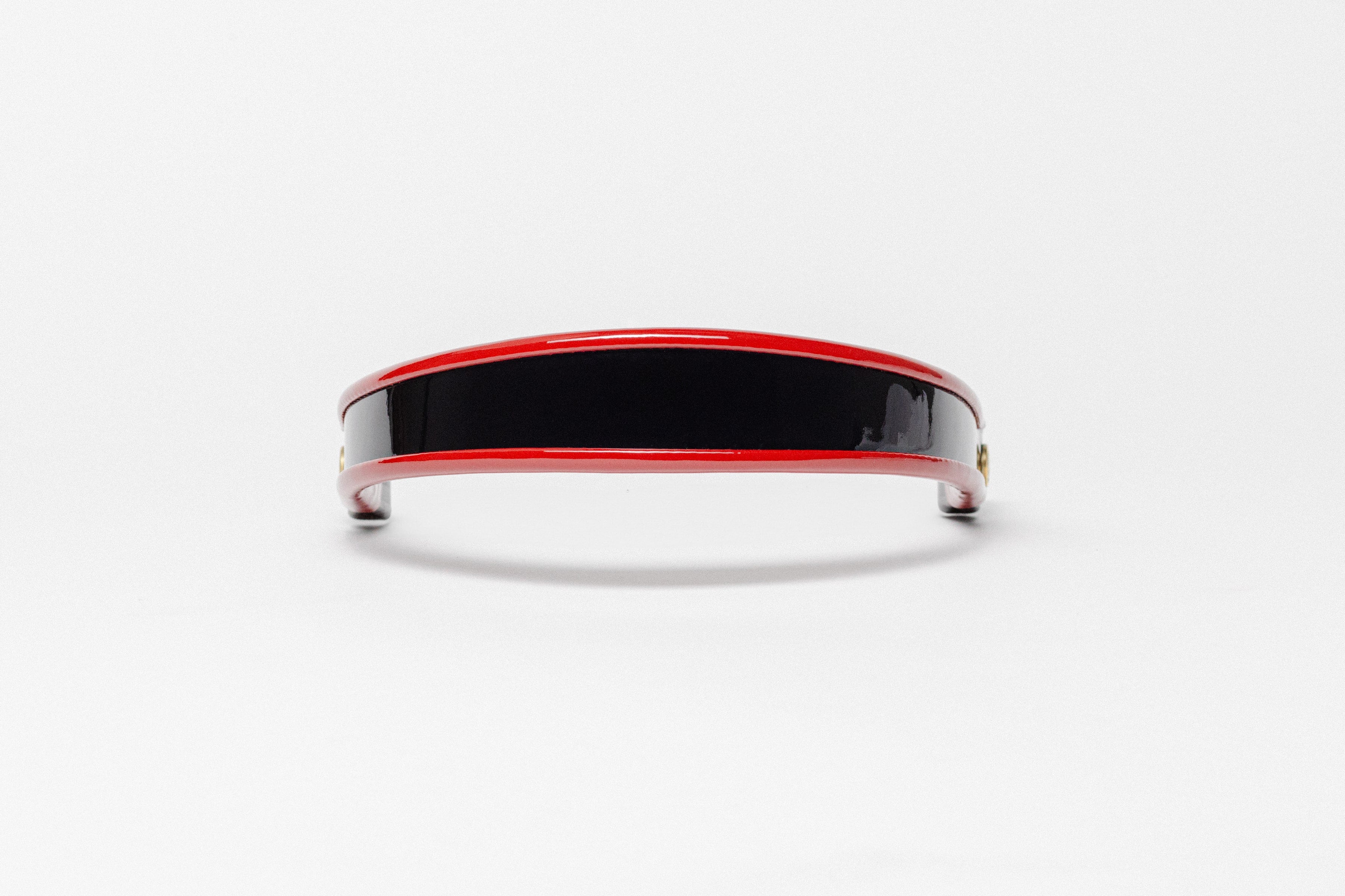 Red and black patent leather browband, wide tapered design, turned edge, polished brass Freedman logo buttons, frontal view.