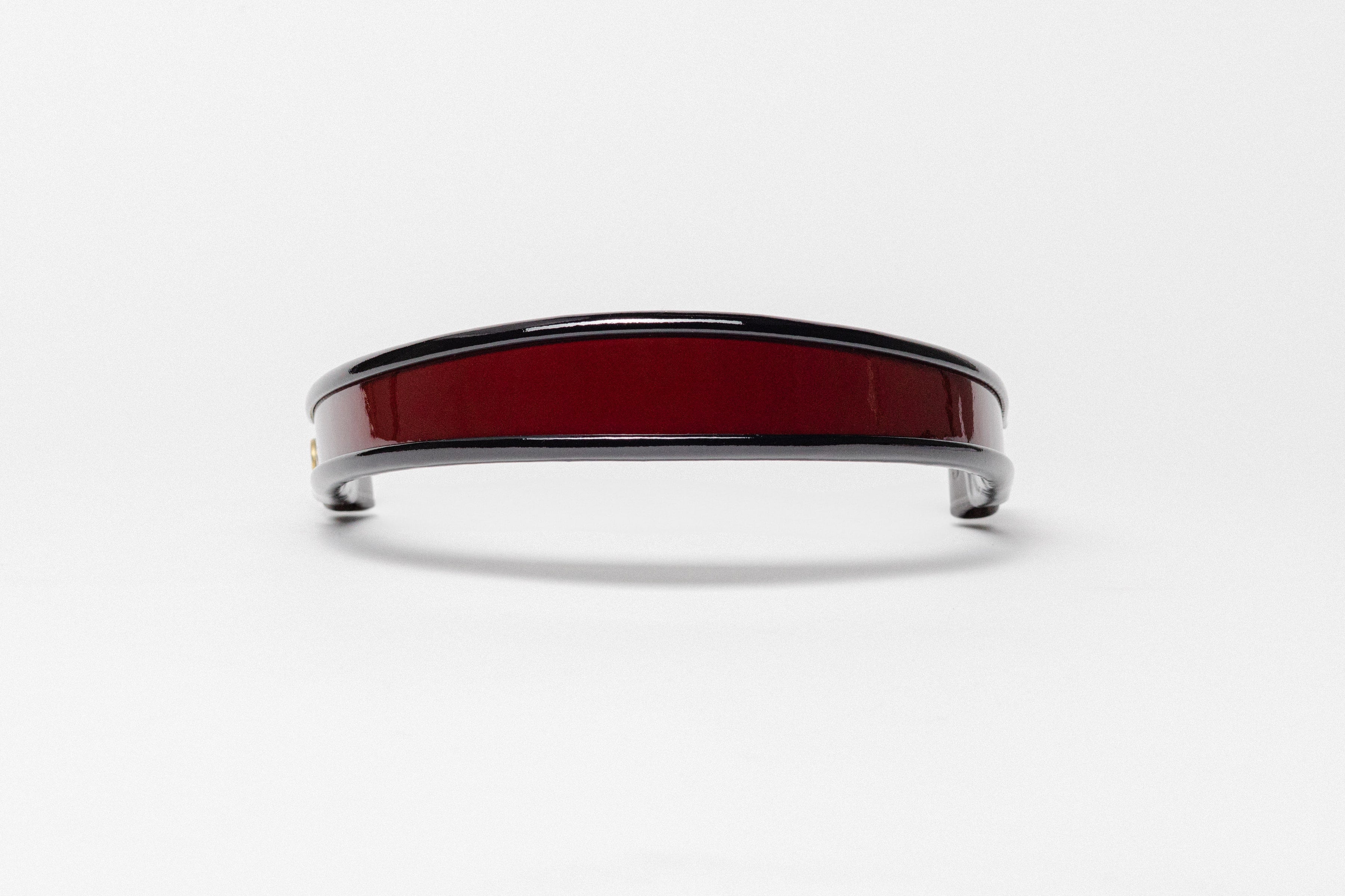 Burgundy and black patent leather browband, wide tapered design, polished brass Freedman logo buttons, and dark leather ends, frontal view.