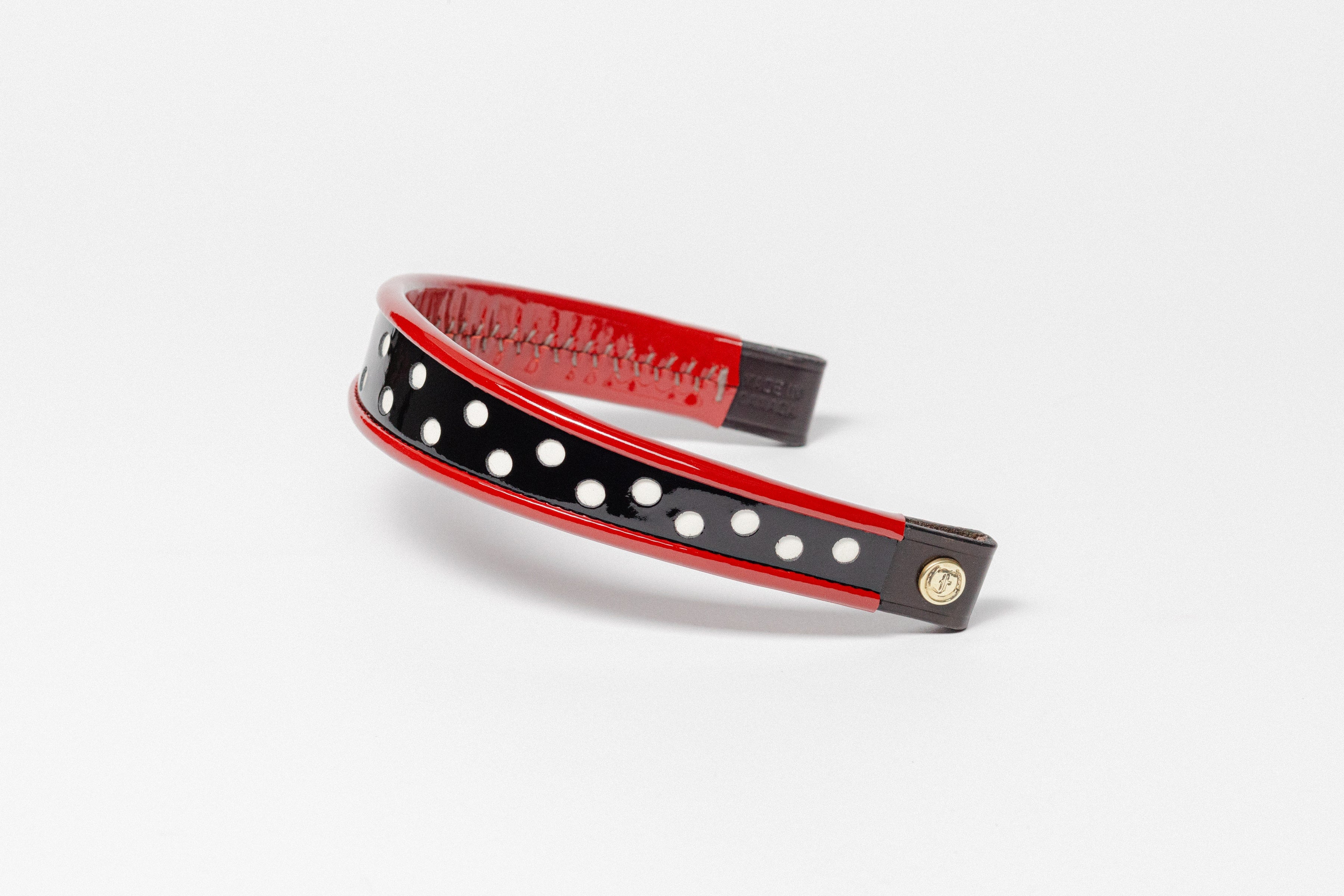 Red and white dot patent leather  browband, wide tapered design, turned edge, dark leather ends with gold button, shown angled.