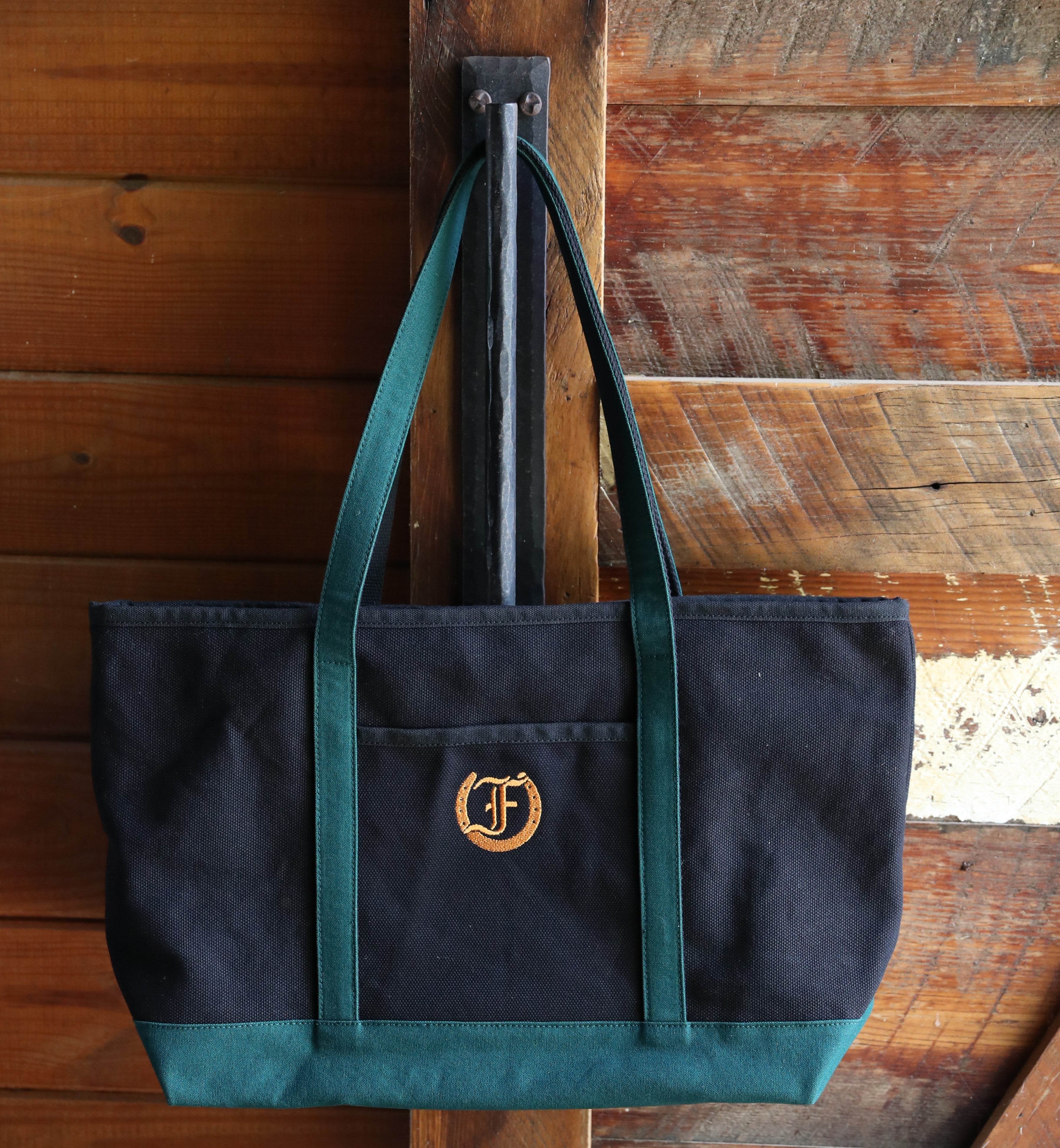 Oxford Large Cotton Tote in black and green with embroidered logo hanging on a wooden surface.