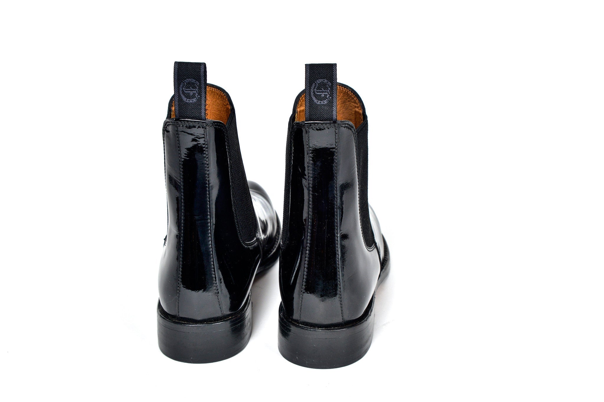 Back view of a pair of black patent leather Adelaide Show Jodhpur Boots, isolated on a white background.