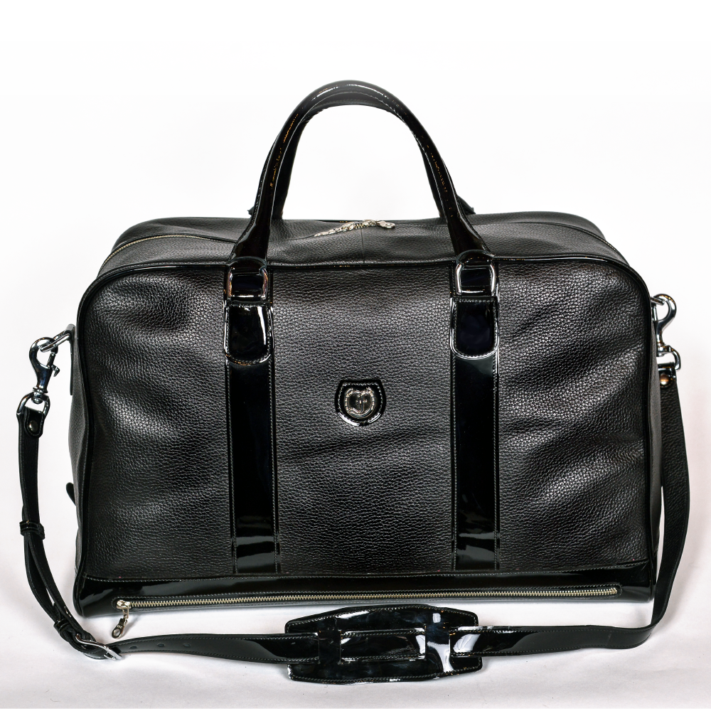 Freedman's Grand Break Duffel Bag, black textured leather, silver hardware, embossed logo, patent leather center straps, dual rolled handles, detachable shoulder strap with padded section, zipper closure, white background.