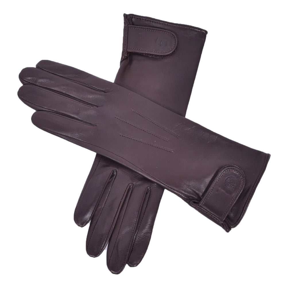 The Yorkville Show Glove, brown leather gloves crossed, with wrist strap and button detail, visible seam stitching, light background.
