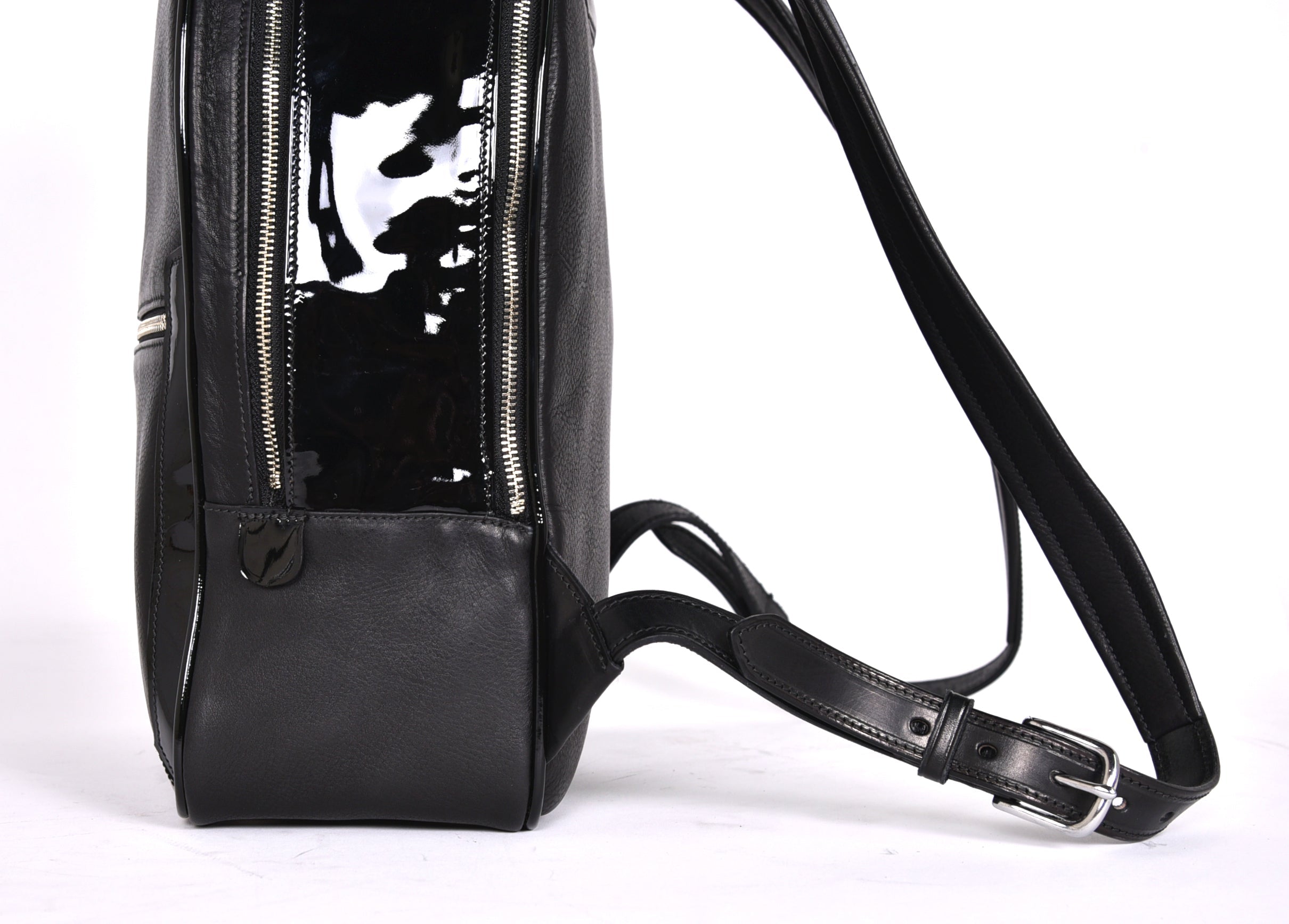 Black leather backpack, The Jaunty by Freedman's, lower view with adjustable strap, patent leather accent, and zipper detail.