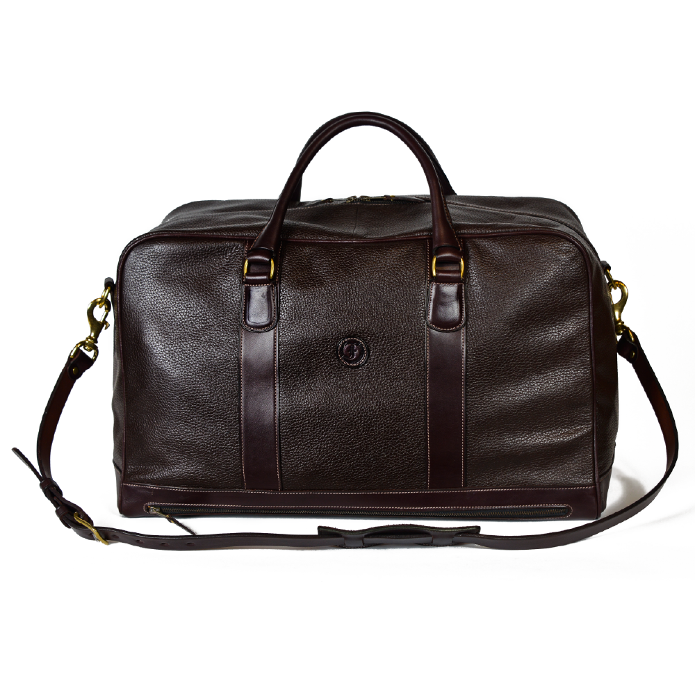 Freedman's Grand Break Duffel Bag, brown textured leather, silver hardware, embossed logo, patent leather center straps, dual rolled handles, detachable shoulder strap with padded section, zipper closure, white background.