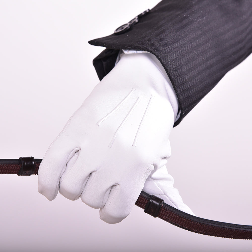 White leather show glove, The Yorkville model, worn on hand holding a riding rein, with jacket sleeve visible.