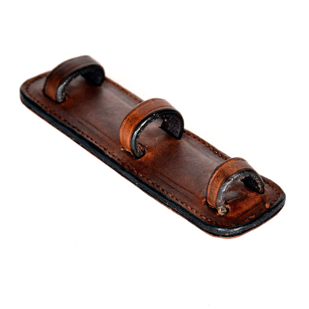 Close-up of an ACTraining tack draw tight caveson strap pad showing leather construction and loop details.