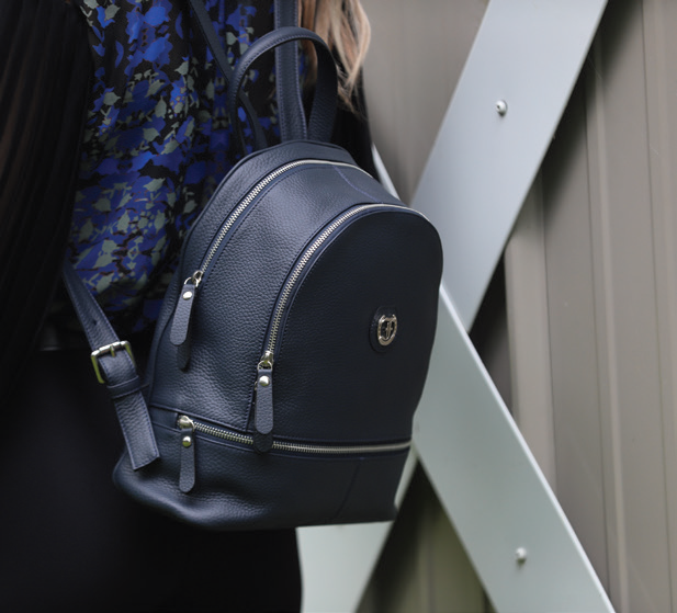 A woman with a navy blue Brougham Backpack, demonstrating its use as a backpack.